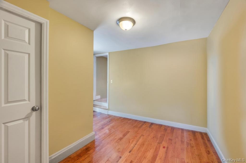 Interior space featuring wood-finish flooring, a white paneled door, and light-colored wall paint