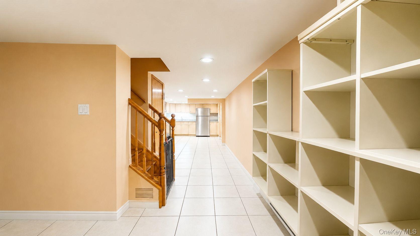Storage area featuring extensive built-in shelving, recessed lighting, and tile flooring