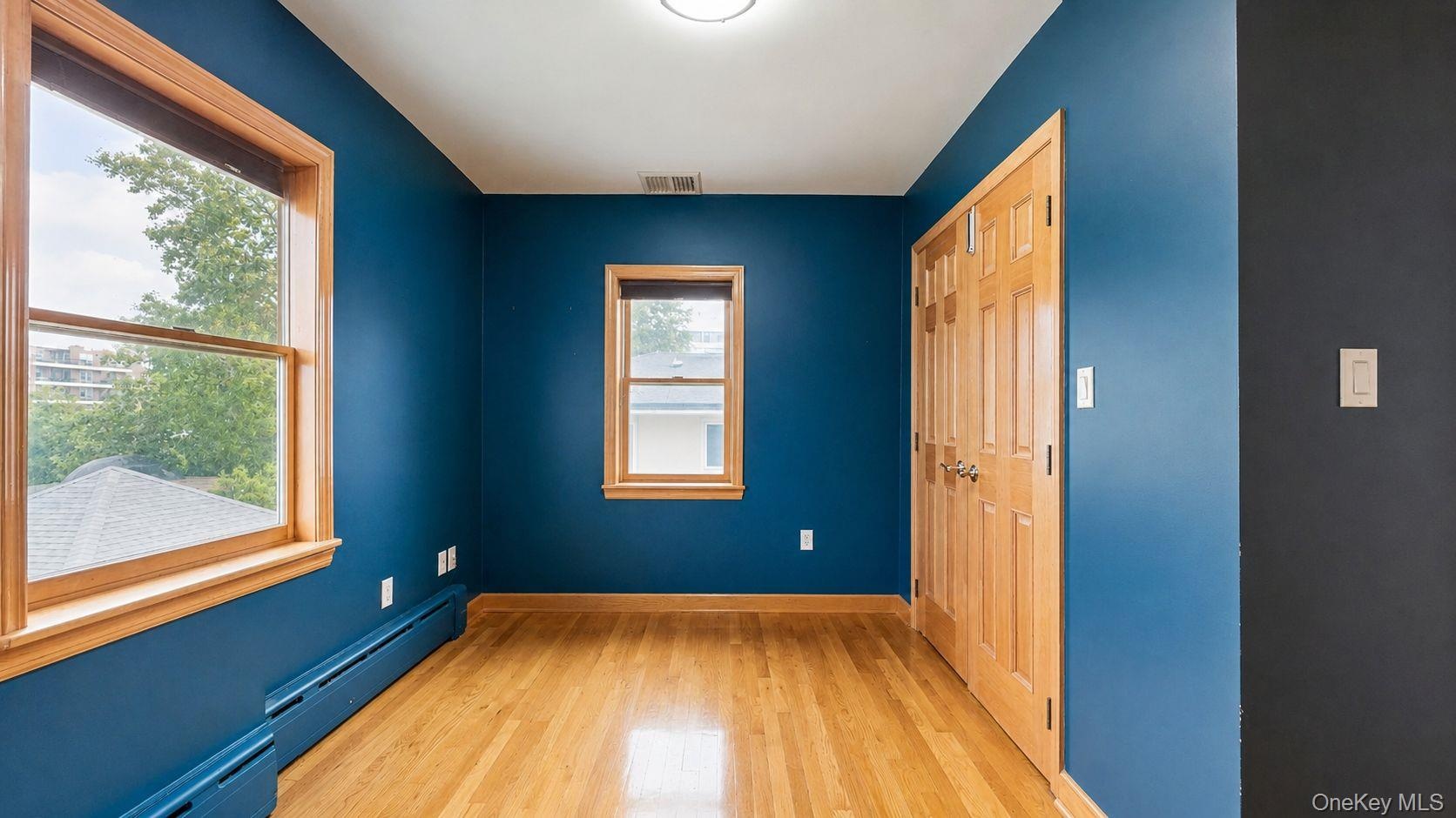 Hardwood flooring featuring natural wood window casings and baseboards