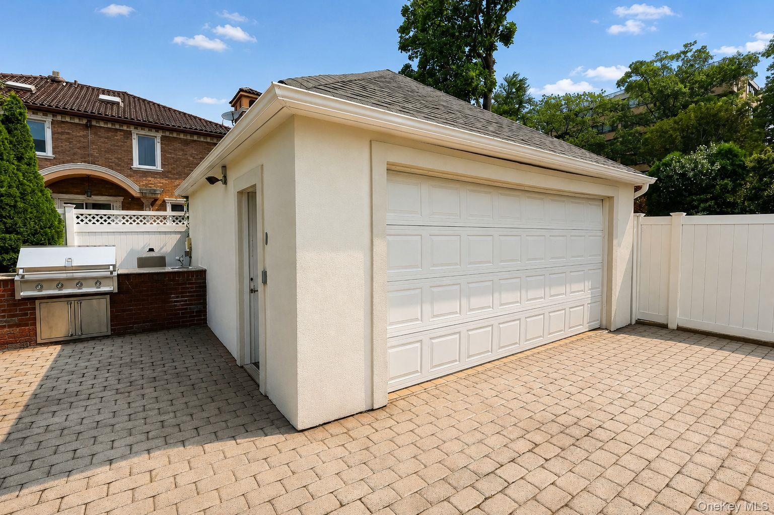 Detached garage with a paneled door, complemented by a paver driveway