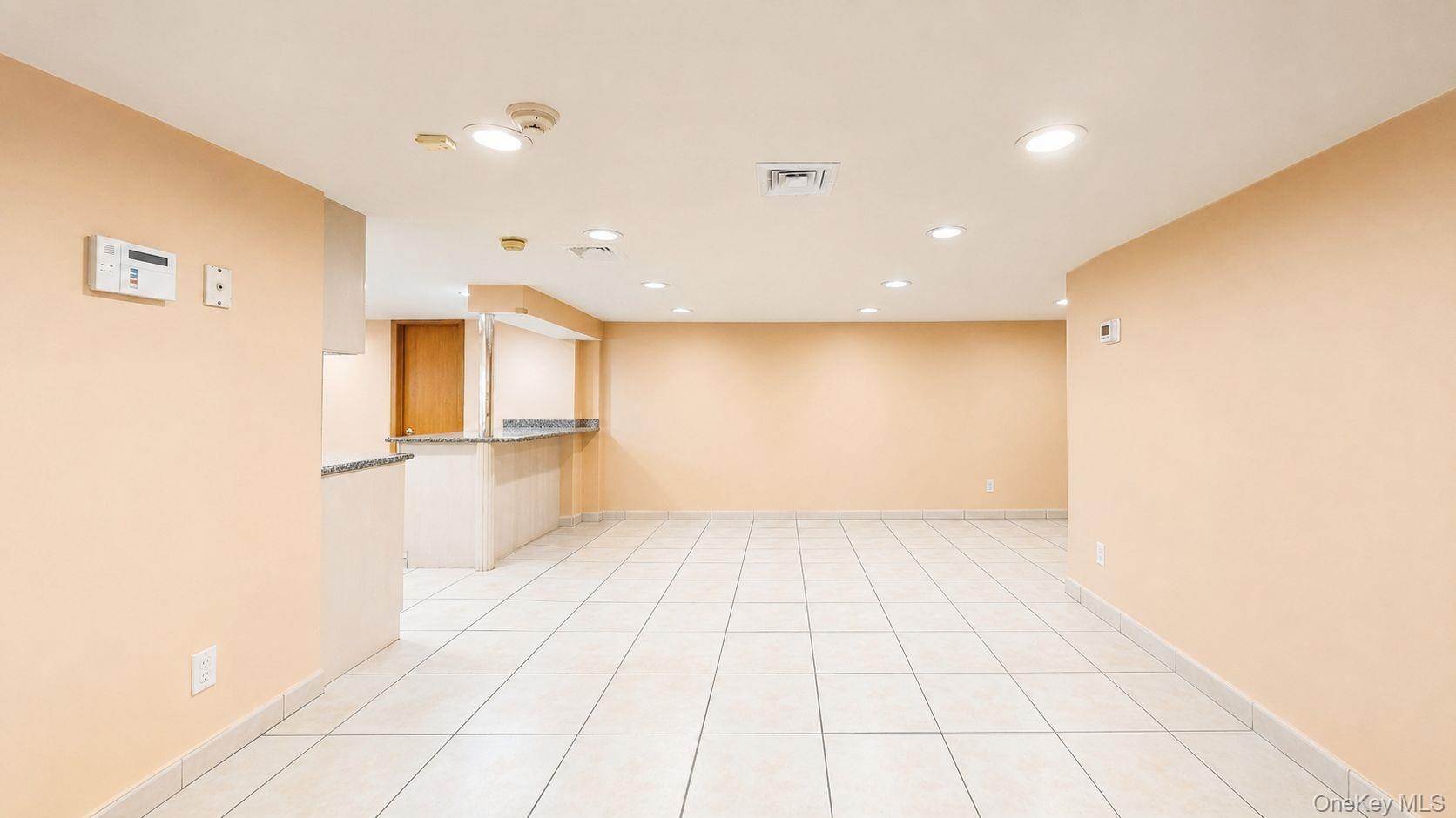 Spacious open-concept area featuring light-toned tile flooring, recessed ceiling lighting, and a neutral wall palette