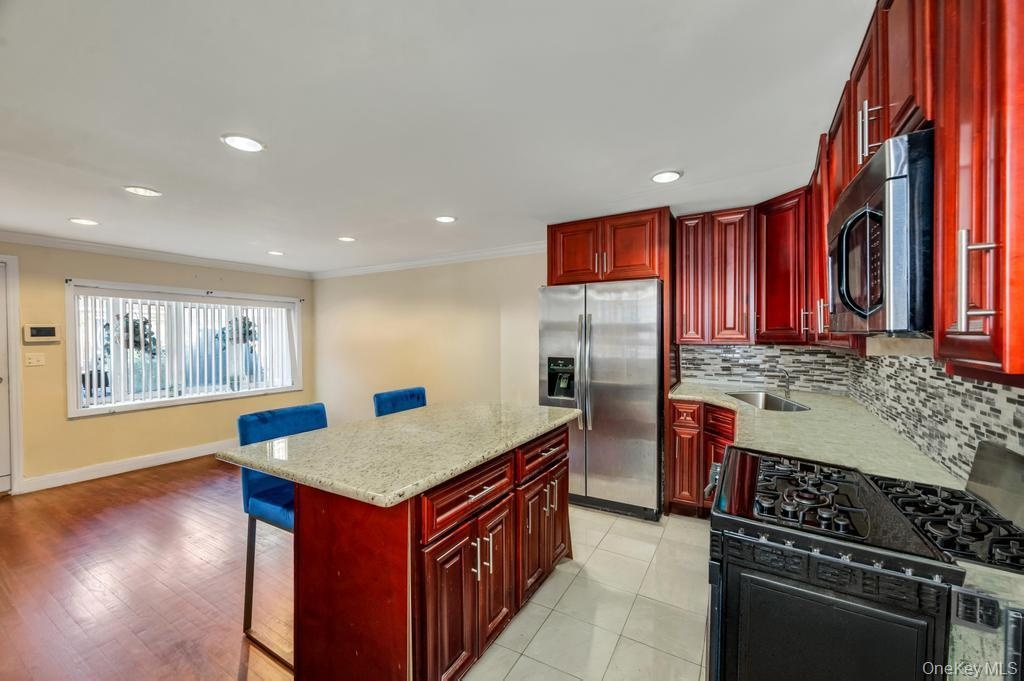 Open-concept kitchen with cherry wood cabinetry, granite countertops, and stainless steel appliances