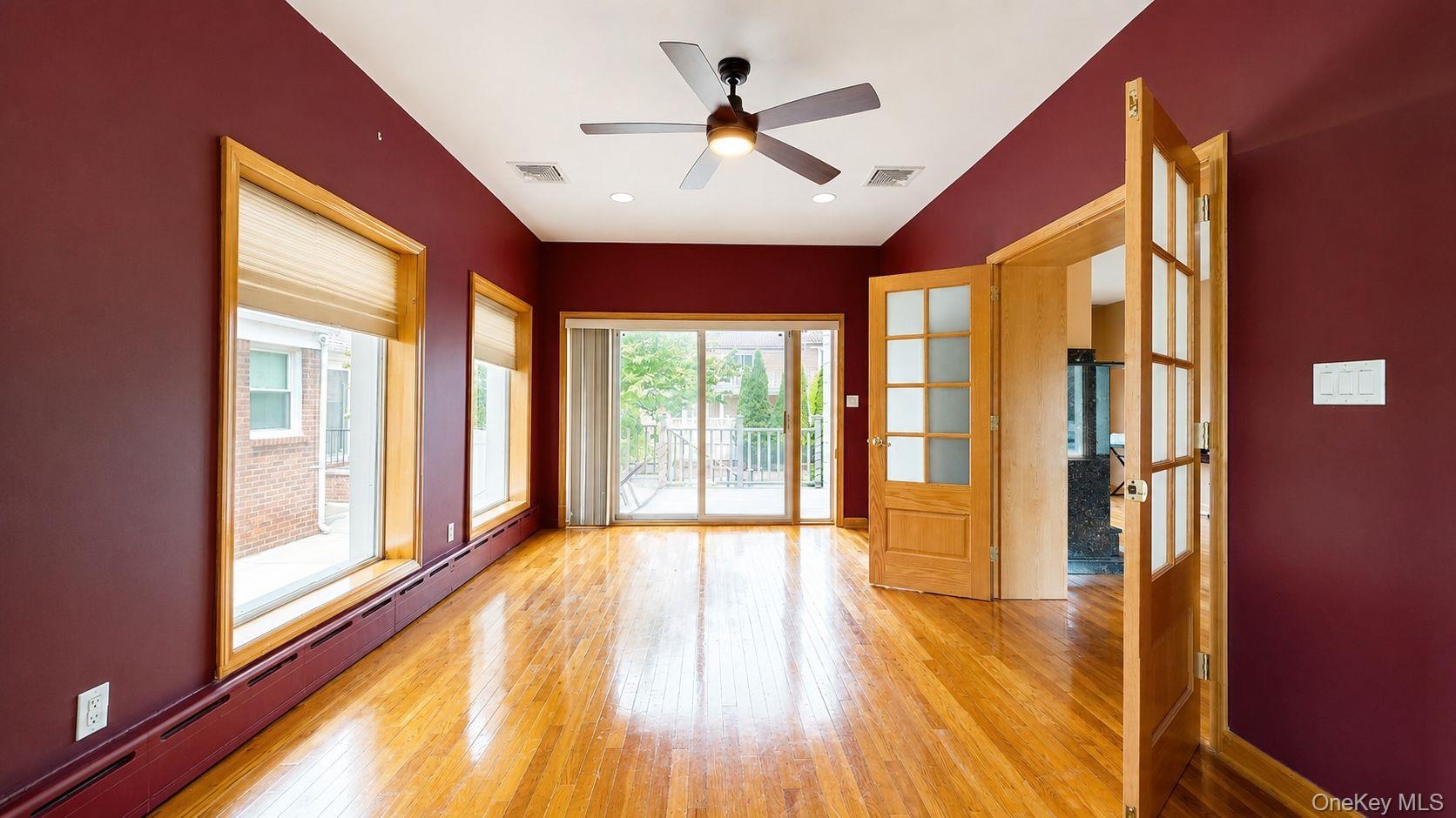 Hardwood flooring throughout this room featuring a ceiling fan, recessed lighting, and two sets of glass-paneled doors