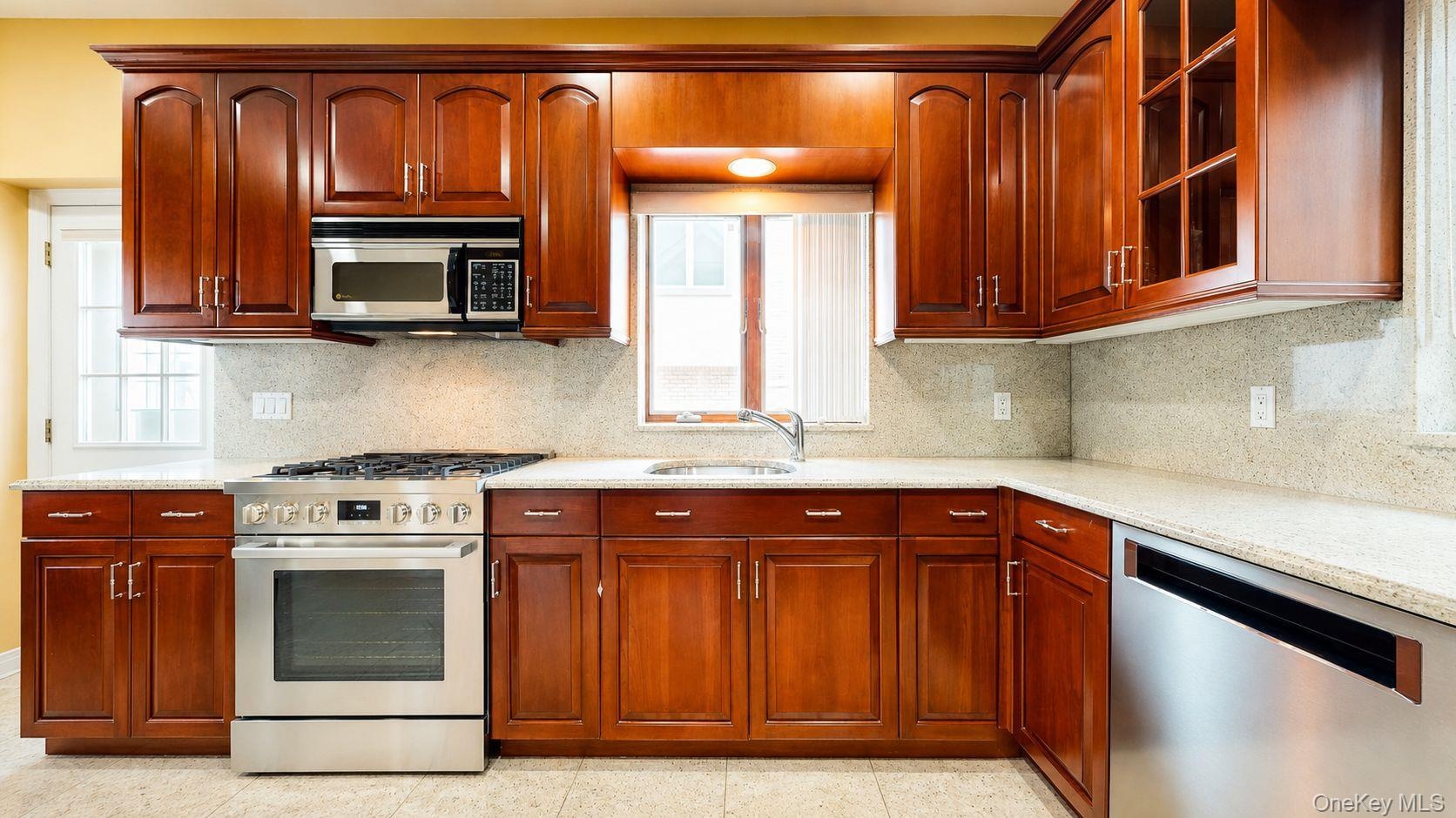 Kitchen featuring wood cabinetry, light-toned countertops, a full stainless steel appliance suite, and a tiled backsplash