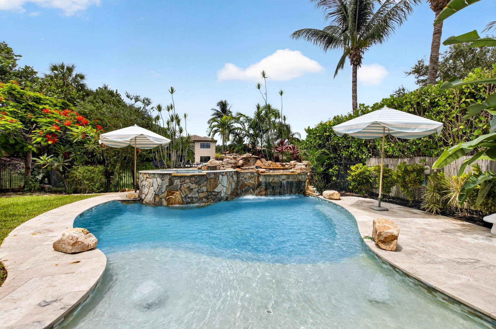Resort-style pool featuring a rock waterfall and integrated spa