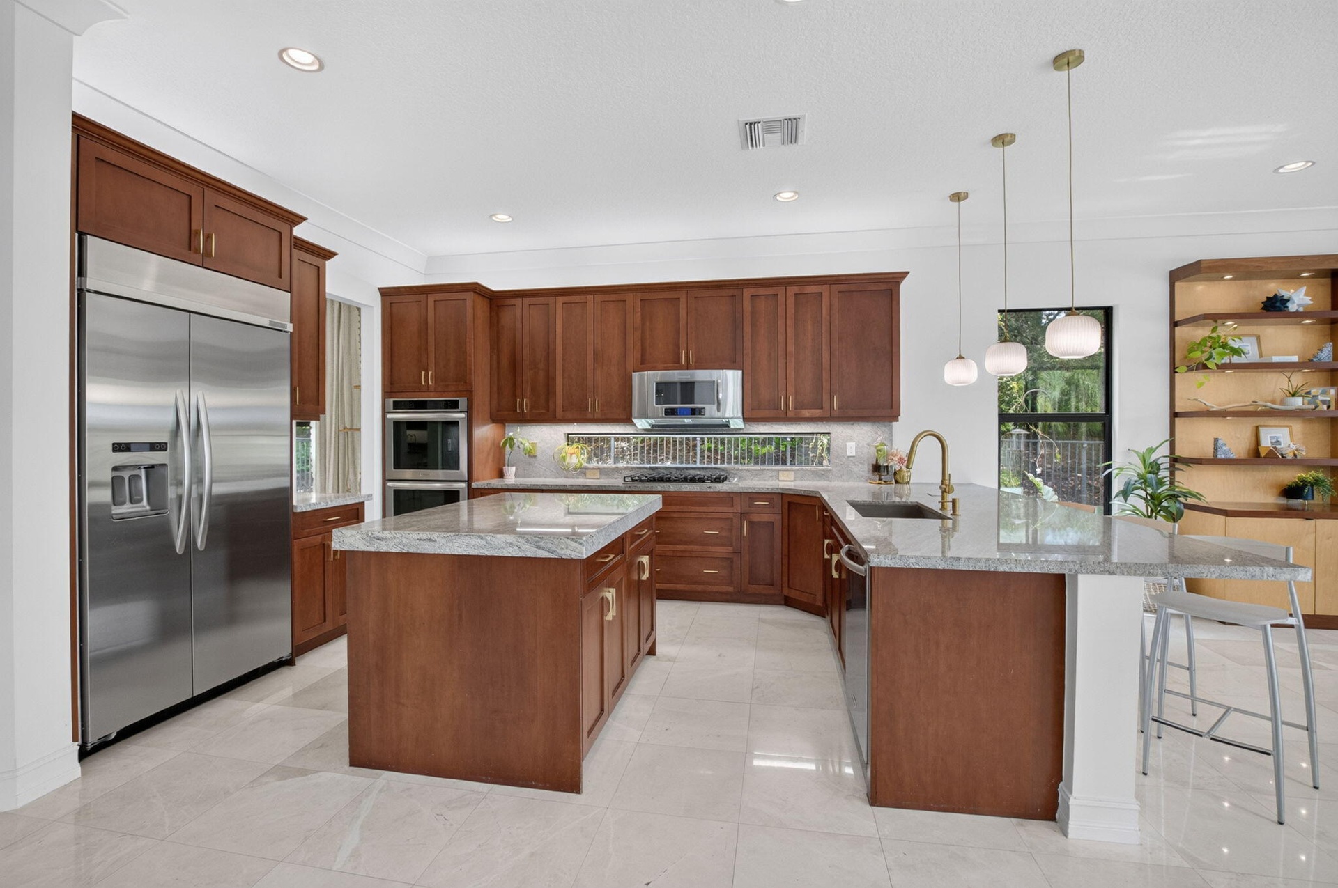 Expansive kitchen featuring wood cabinetry, stainless steel appliances, a center island with countertop seating, and recessed lighting