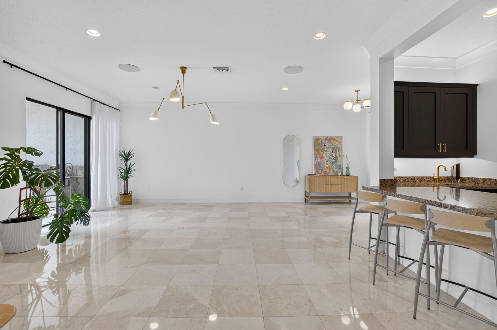 Expansive living area featuring large format tile flooring and a wet bar with dark cabinetry and a granite-style countertop