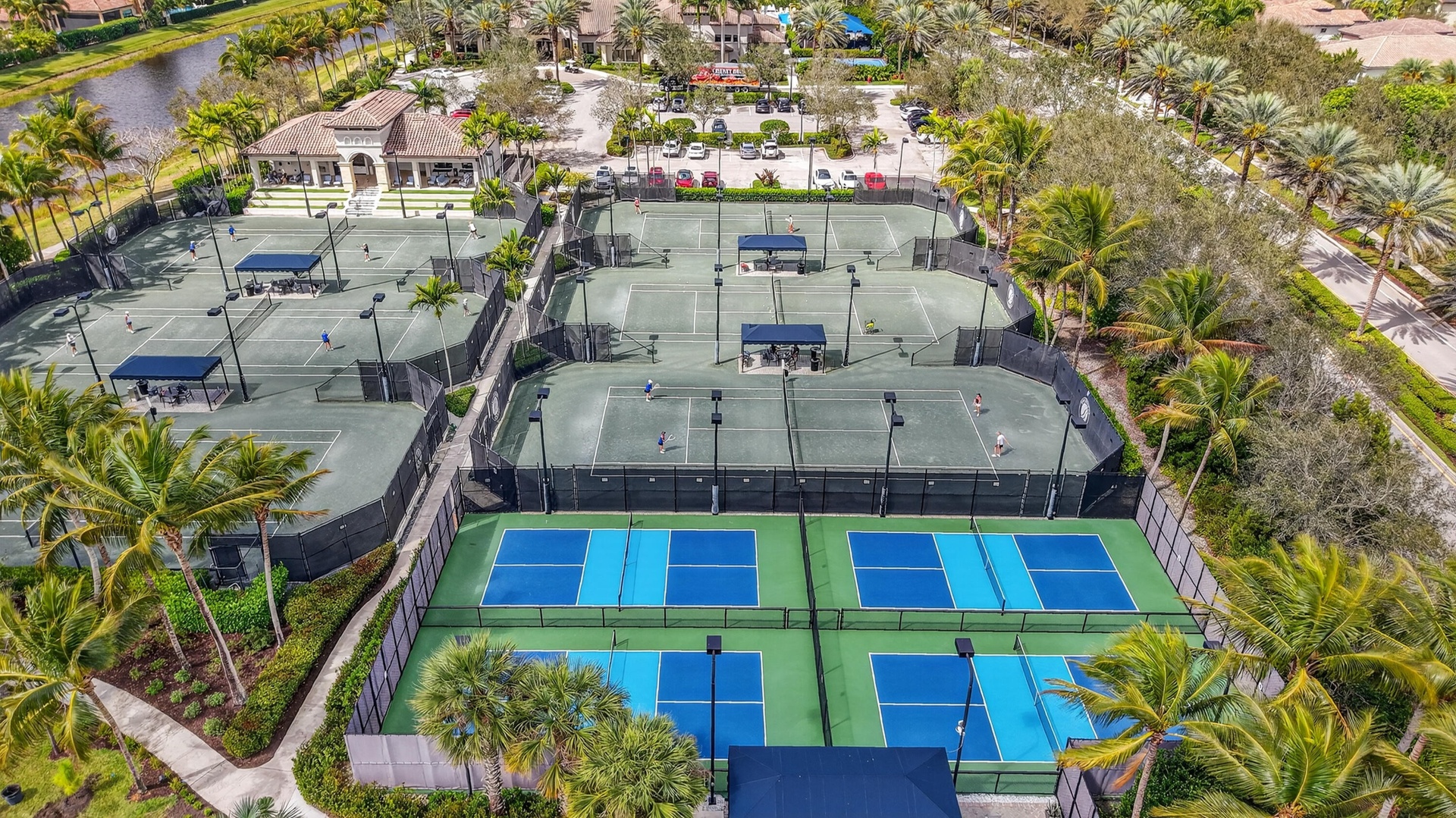 Expansive tennis and pickleball courts featuring perimeter fencing, spectator shelters, and court lighting
