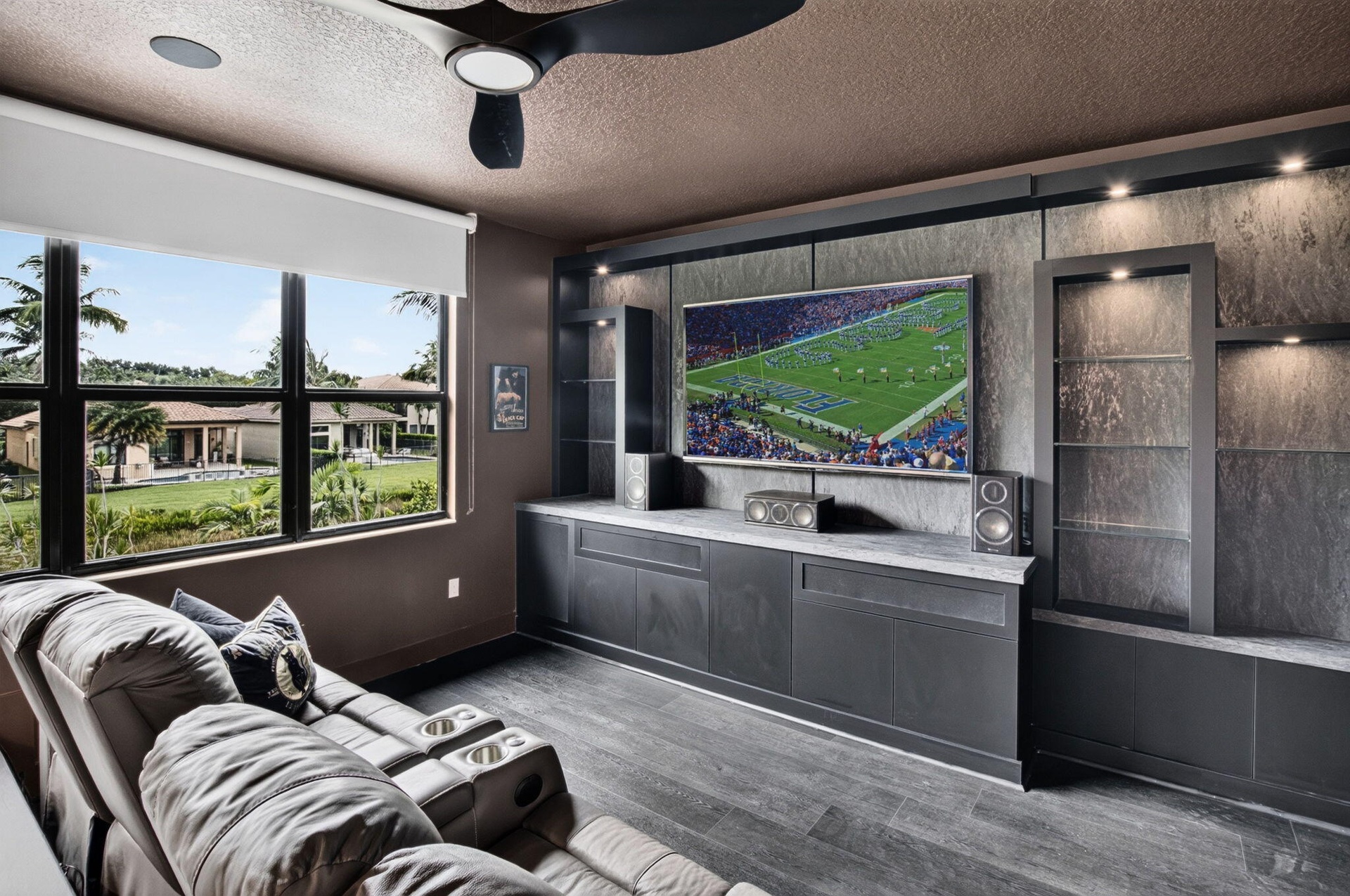 Custom built-in media console with stone-finish accent wall, integrated display shelving, and recessed lighting
