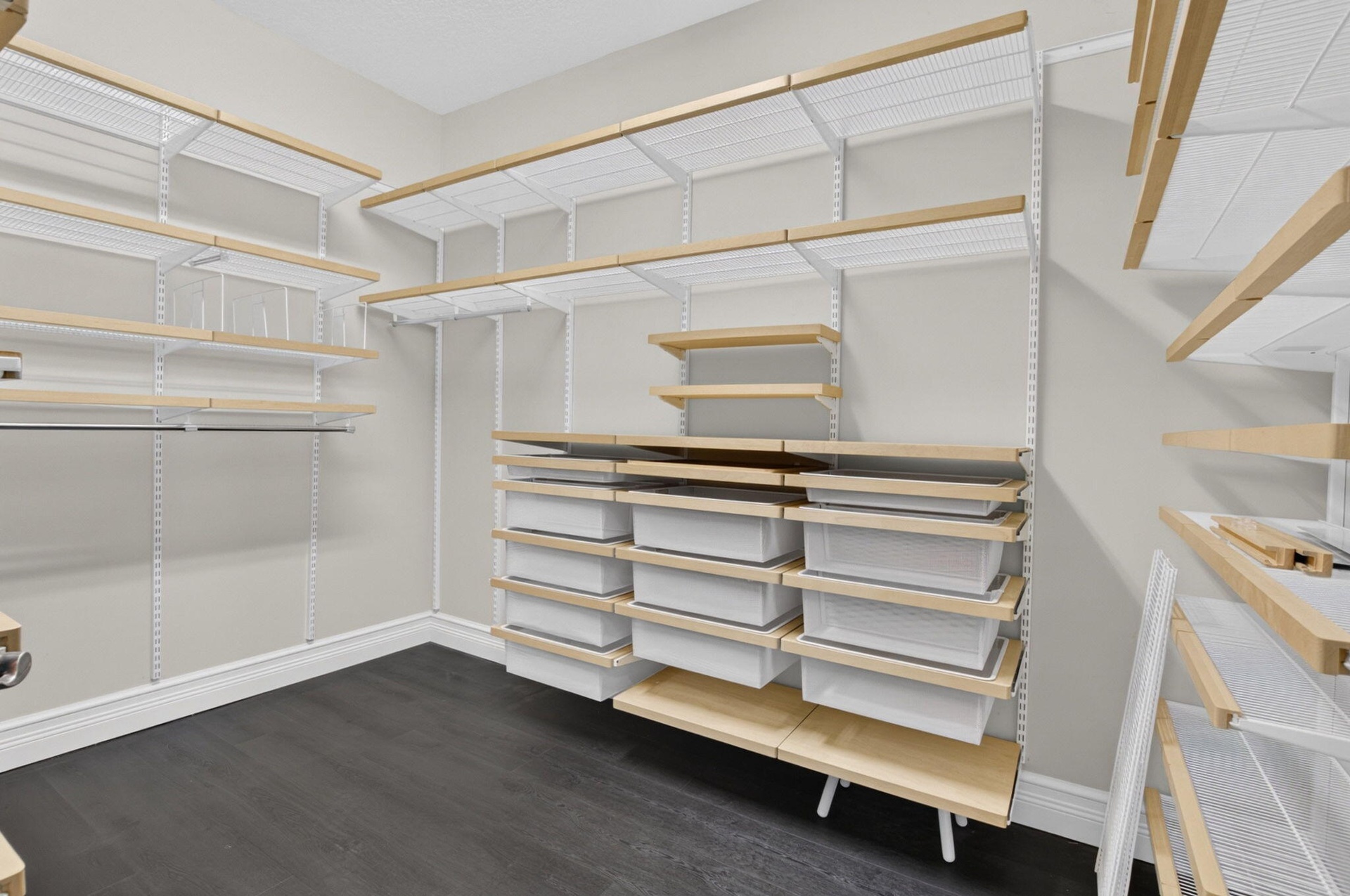 Customizable closet system featuring wood-finish shelving, integrated drawers, hanging rods, and dark wood-finish flooring