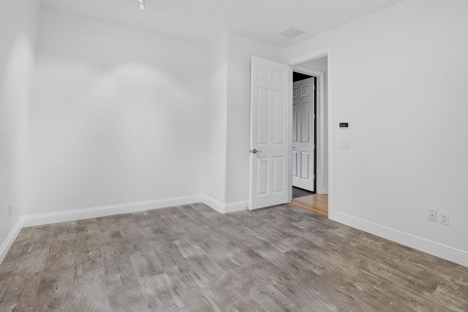 Interior room featuring light wood-finish flooring, white walls, and white baseboards