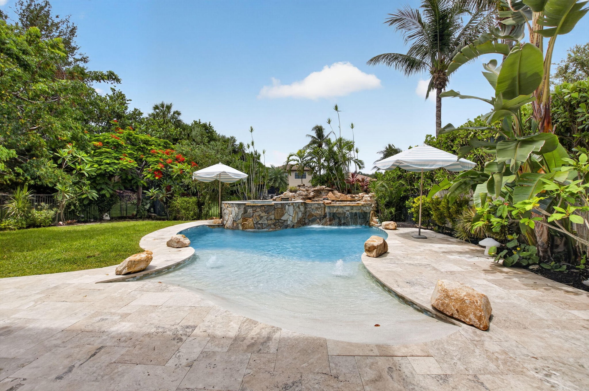 Freeform pool with a rock waterfall feature and integrated sun shelf