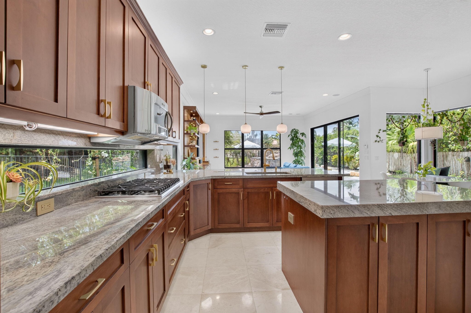 Gourmet kitchen featuring rich wood cabinetry, light-toned countertops, a built-in gas cooktop, and large sliding glass doors leading to the exterior
