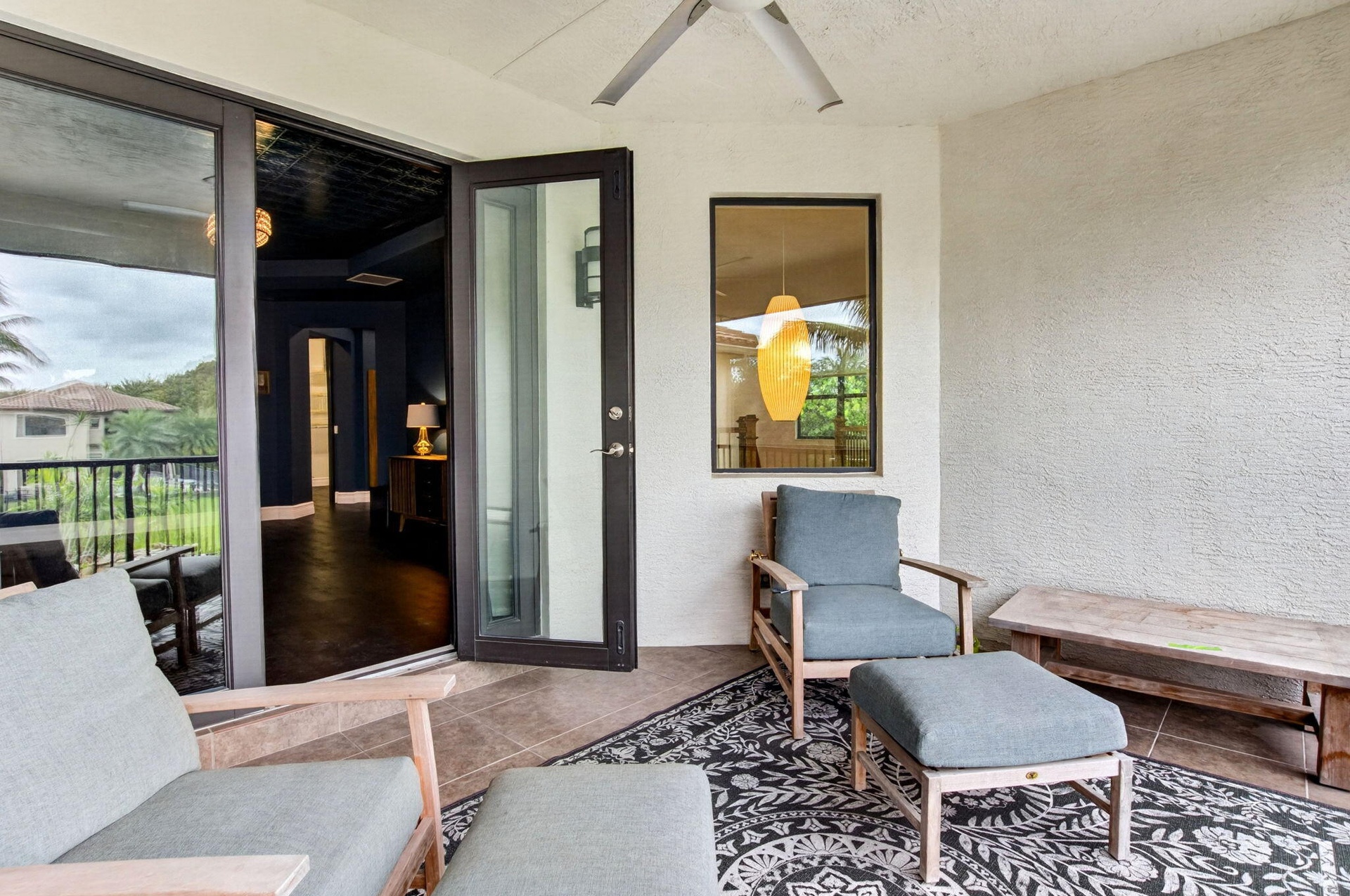 Outdoor patio featuring a textured stucco finish, dark framed glass sliding doors, and a ceiling fan