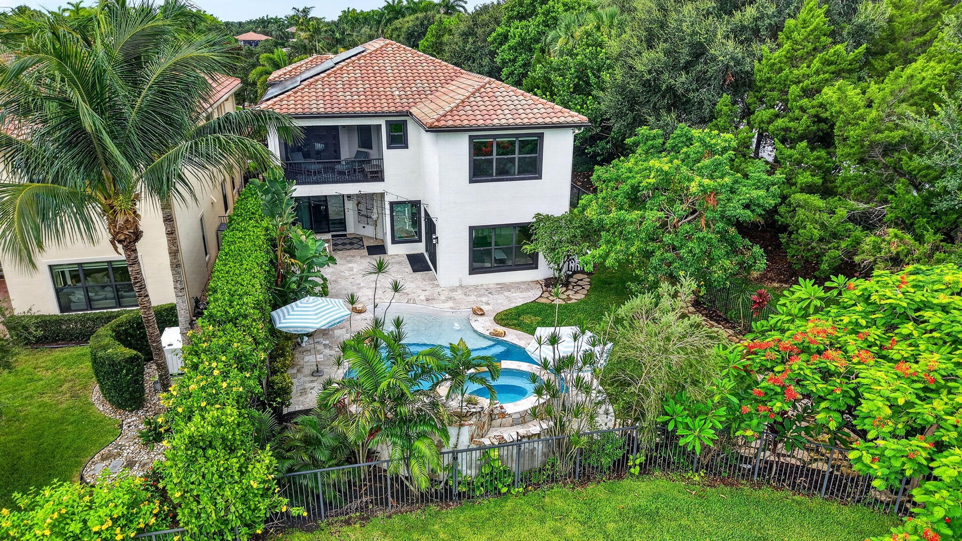 Backyard oasis featuring a freeform swimming pool with integrated spa, surrounded by extensive hardscaping