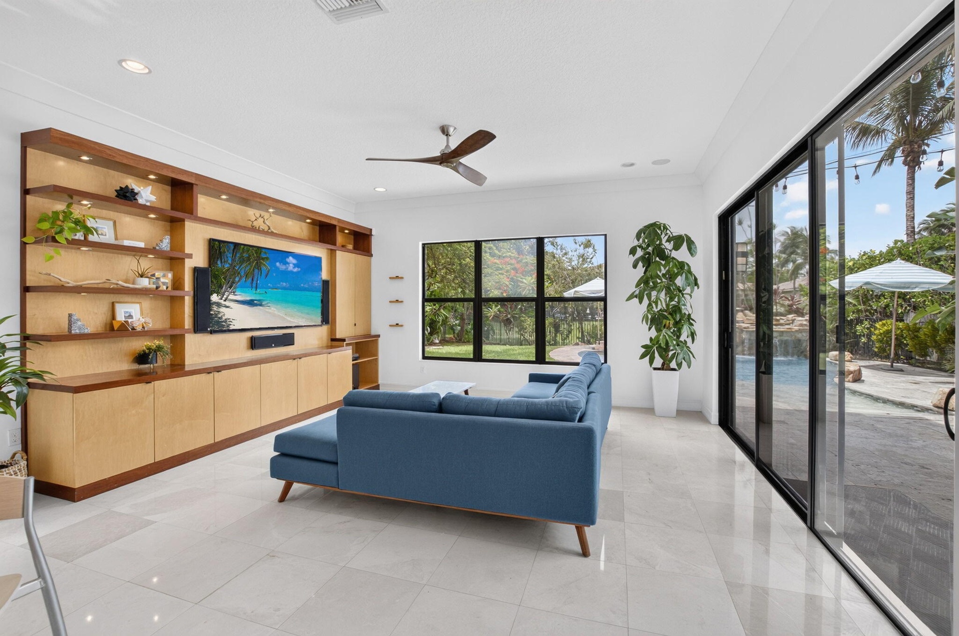 Bright living area featuring a custom built-in entertainment center with integrated lighting, wood-finish shelving, and cabinetry