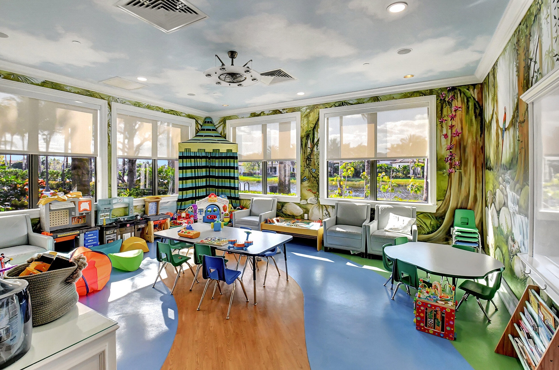 Spacious room featuring panoramic windows, custom mural artwork, recessed lighting, and a multi-toned flooring design with wood-finish and blue sectio