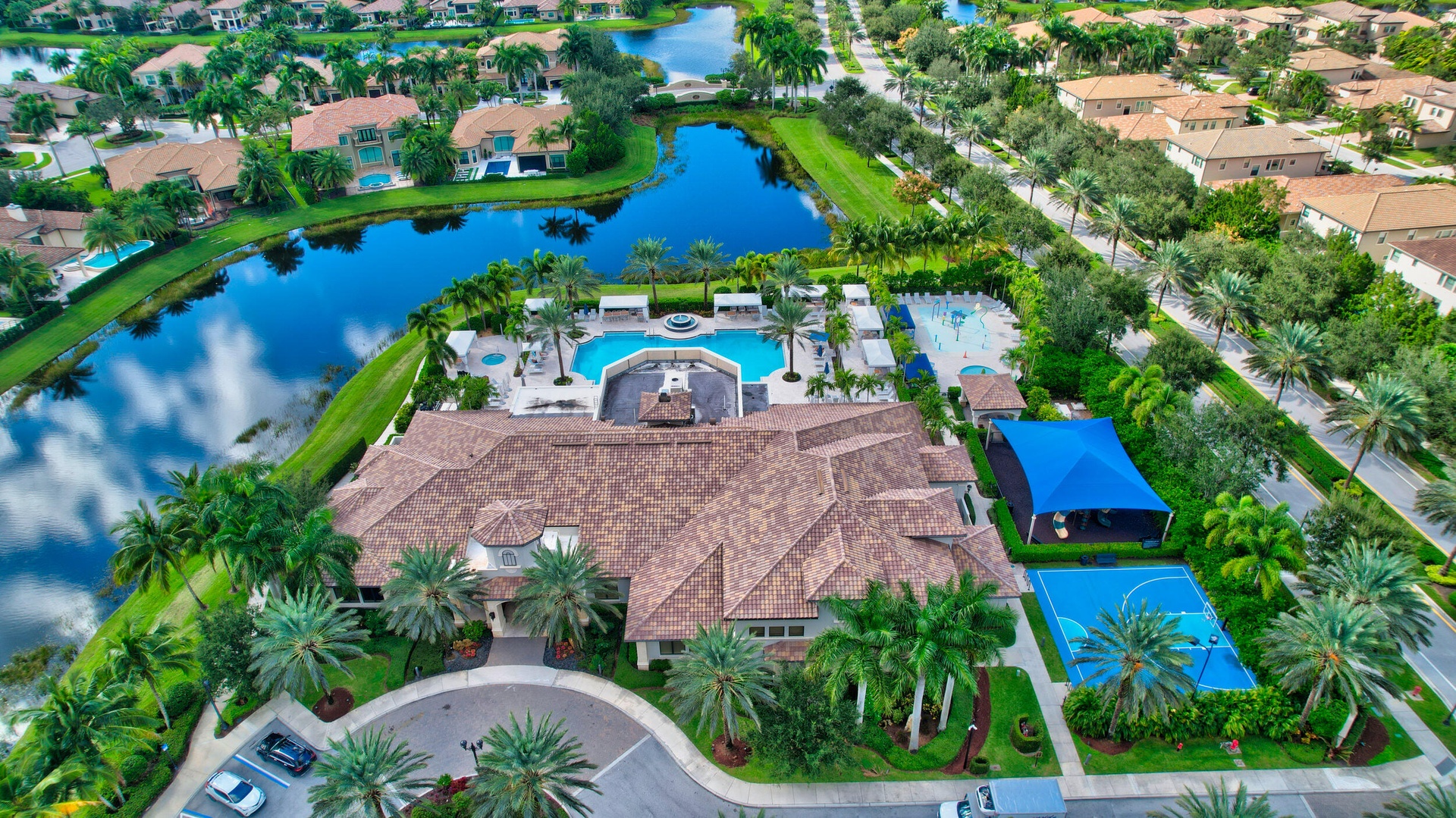 Expansive community amenities including a multi-level resort-style swimming pool, a full-size basketball court, and a covered recreation area, all sit