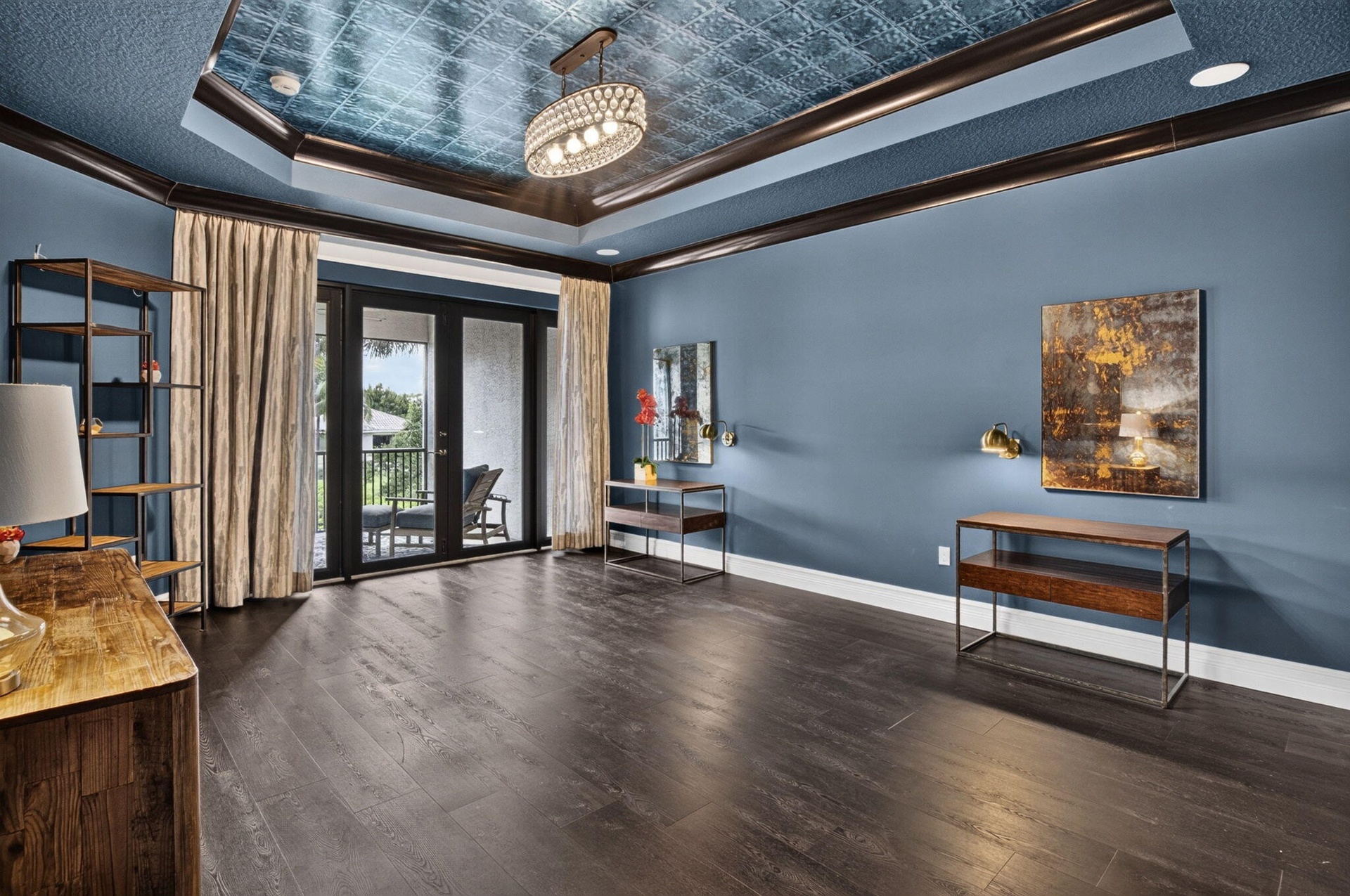 Hardwood-finish flooring complementing a tray ceiling with a blue textured inlay and chandelier