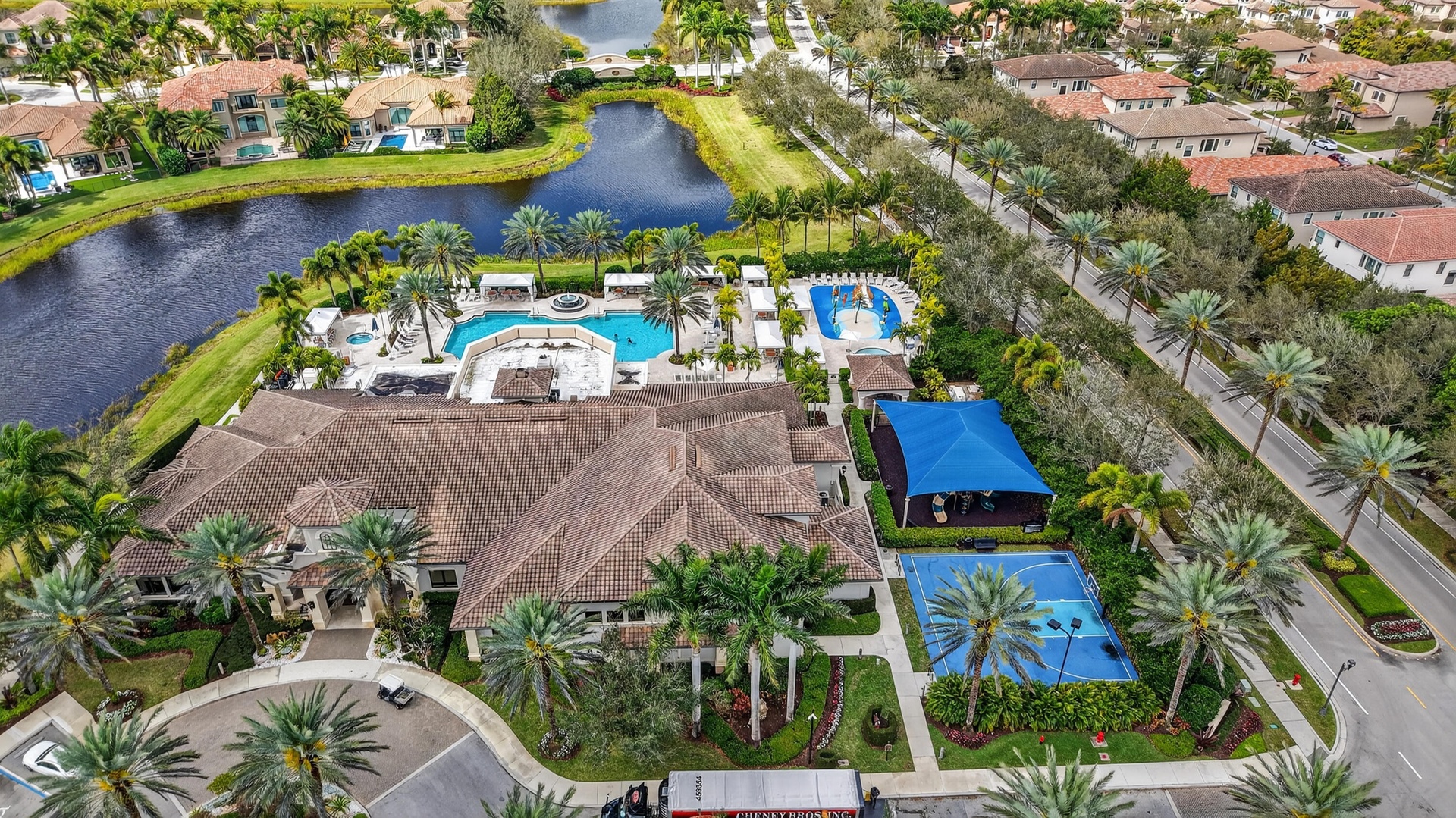 Expansive community amenities featuring multiple pools, sport courts, and a central clubhouse with a tiled roof