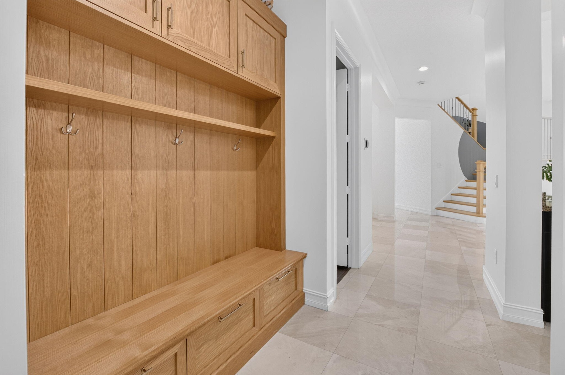 Built-in wood mudroom storage featuring a bench, shelving, and upper cabinetry