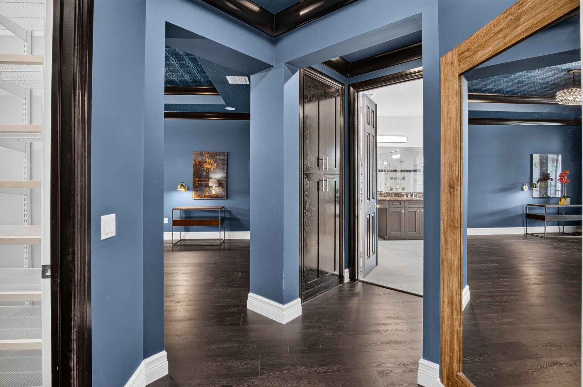 Deep blue walls with white baseboards, dark wood-finish flooring, and dark wood trim