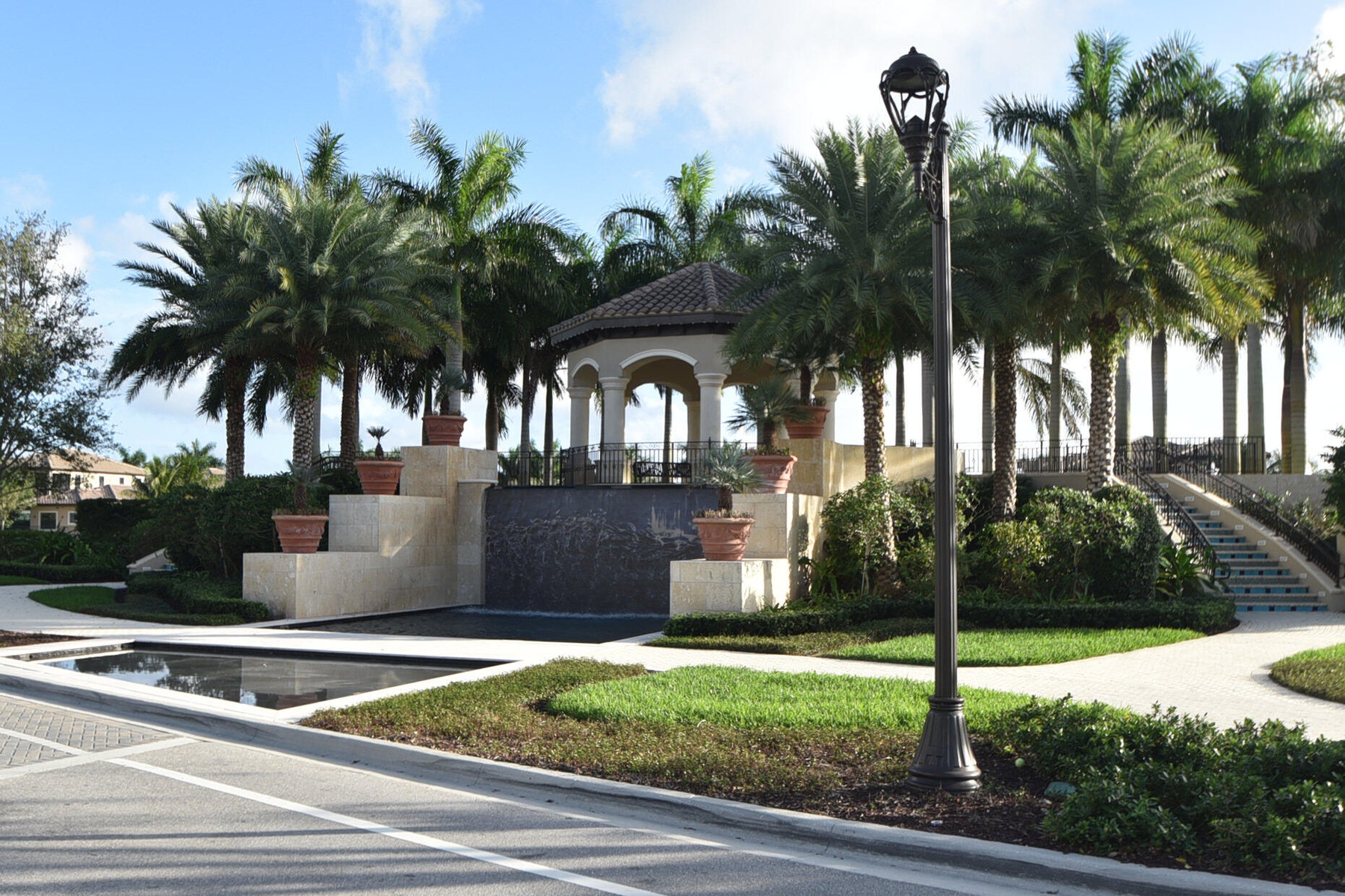 Lush landscaping featuring mature palm trees and a decorative fountain with a tiered stone base