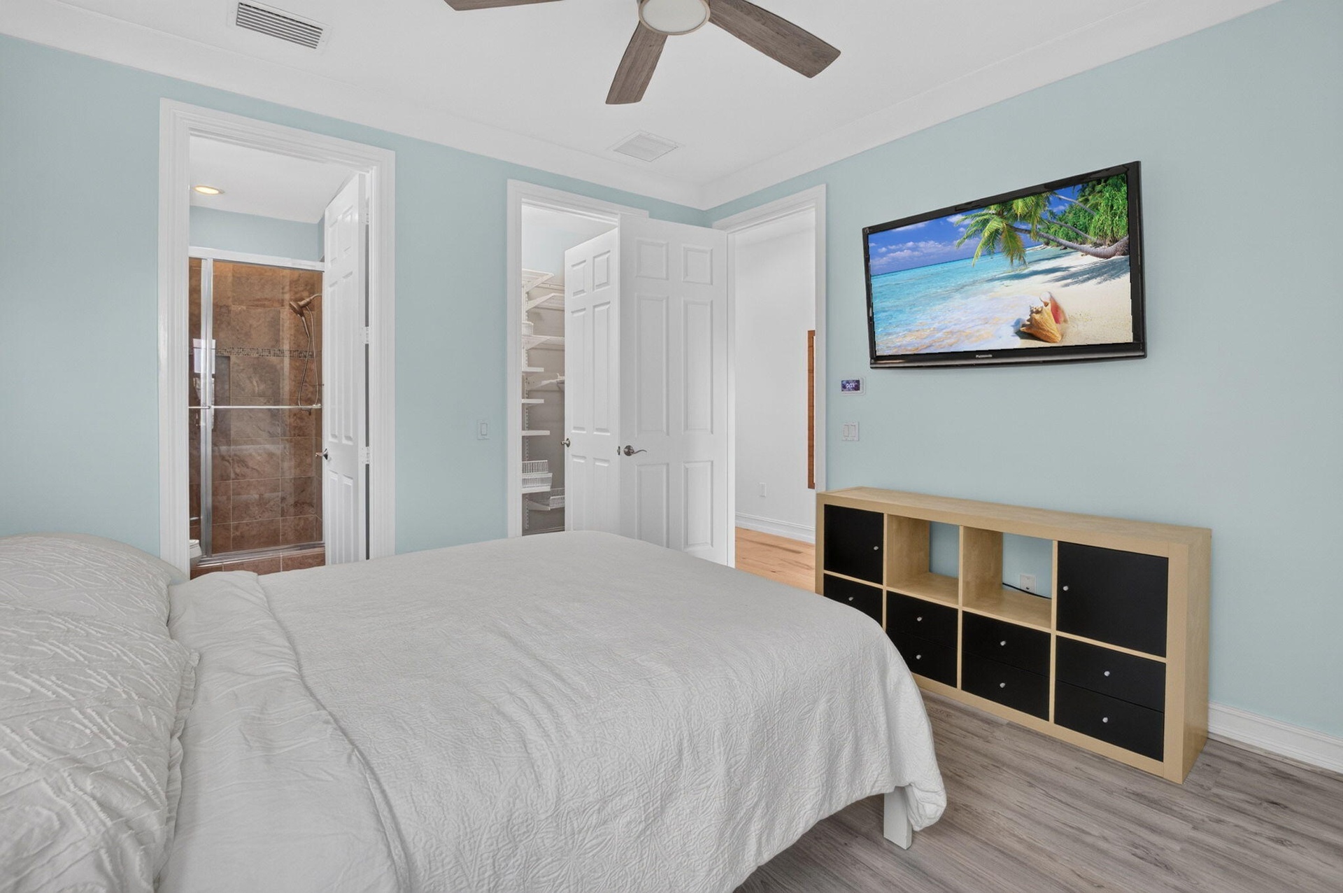 Bedroom featuring a ceiling fan, light blue wall paint, wood-finish flooring, and crown molding