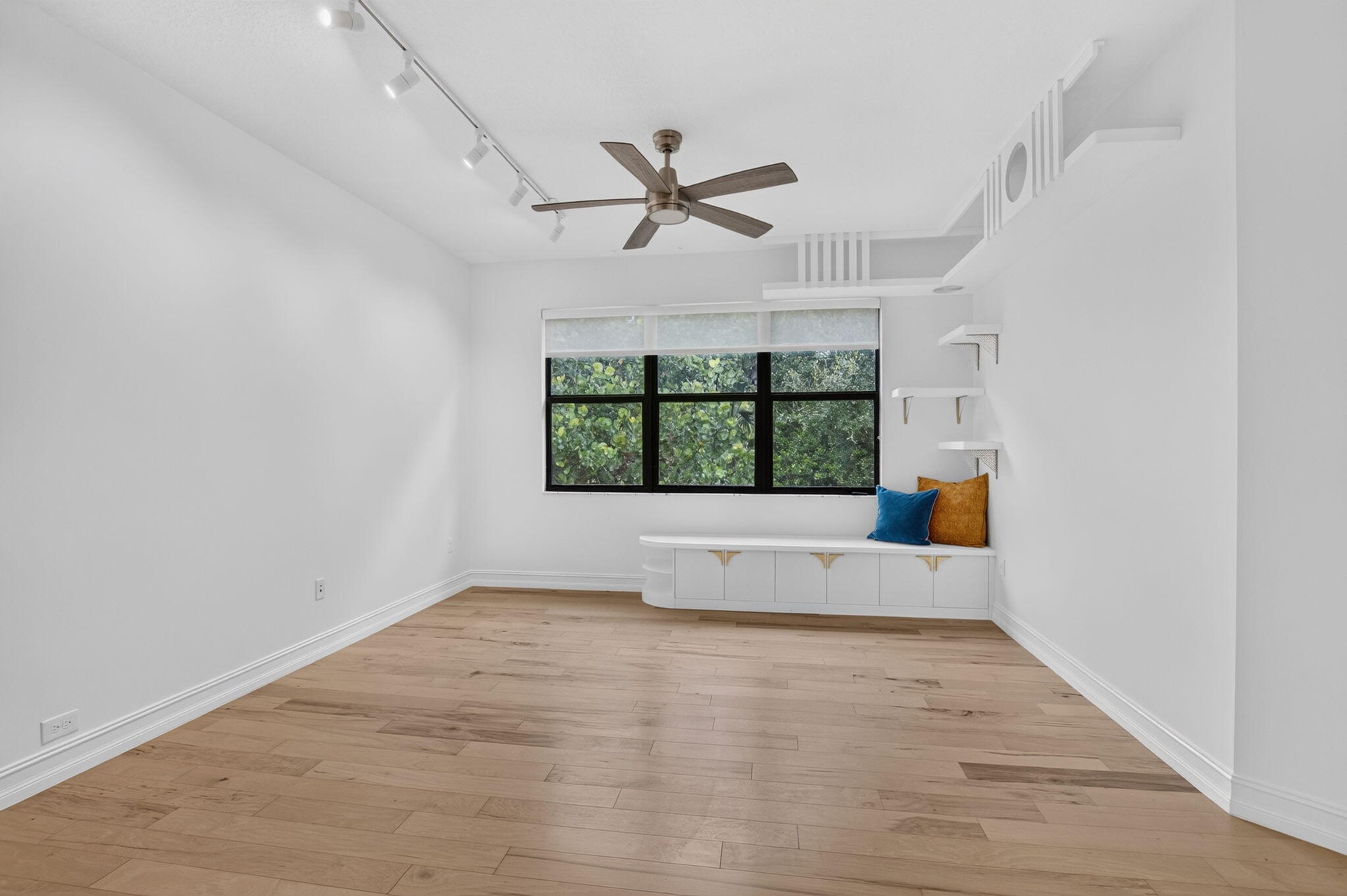 Light wood-finish flooring with white baseboards and window trim