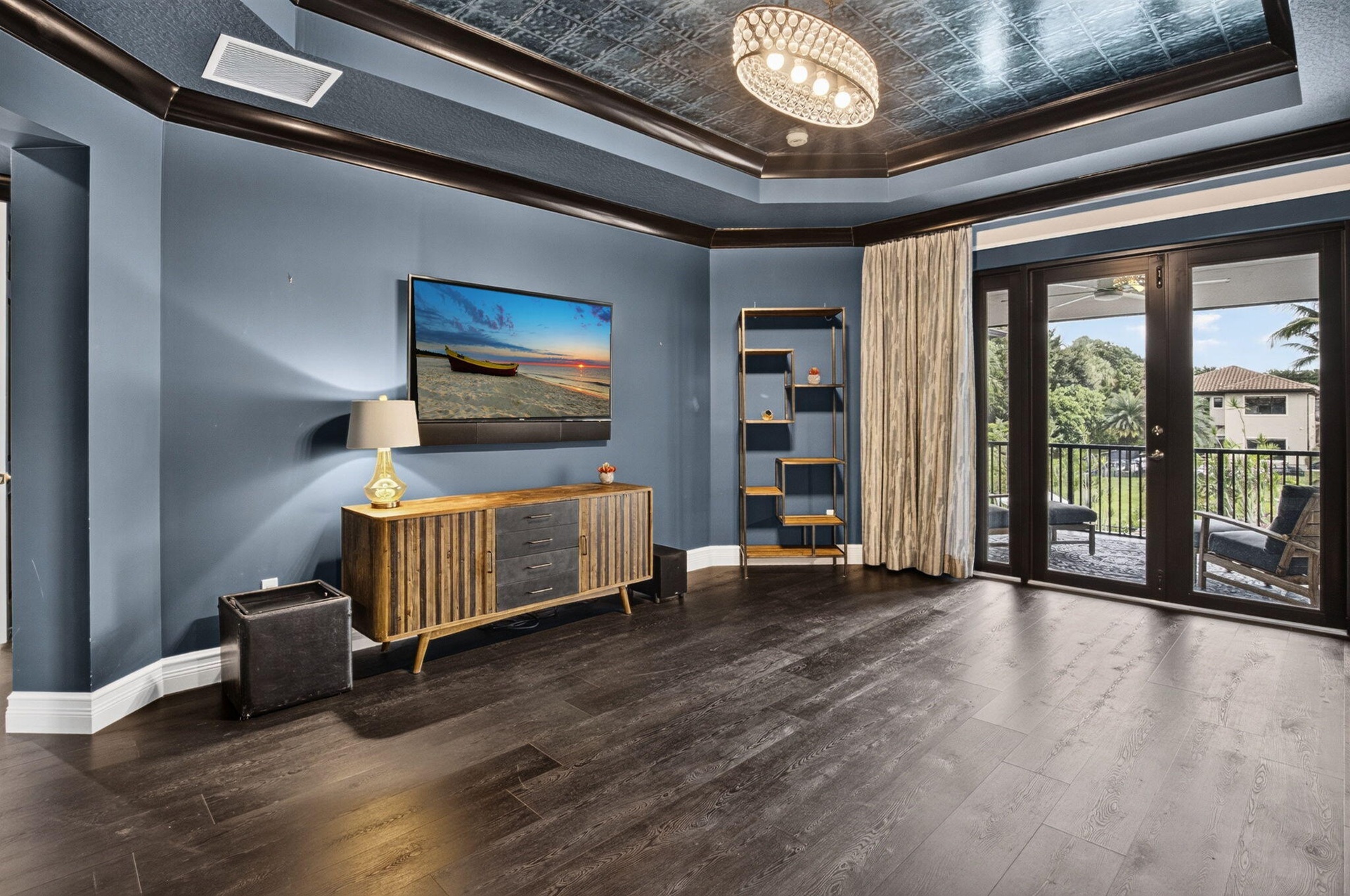 Spacious room featuring dark wood-finish flooring, a tray ceiling with a textured metallic finish, and dark trim