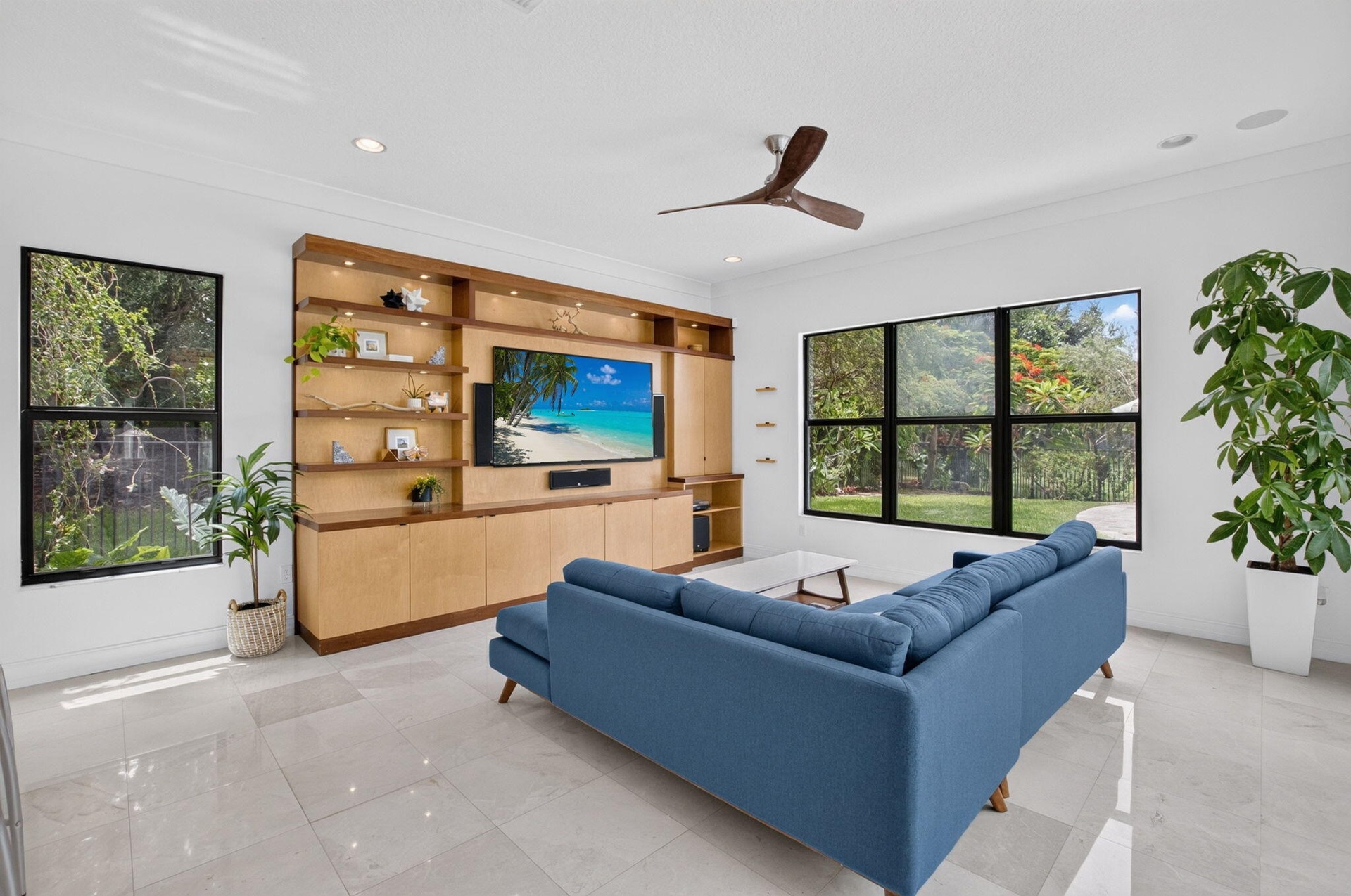 Living area featuring a full-wall built-in entertainment unit with shelving and cabinetry, large format tile flooring, and recessed lighting