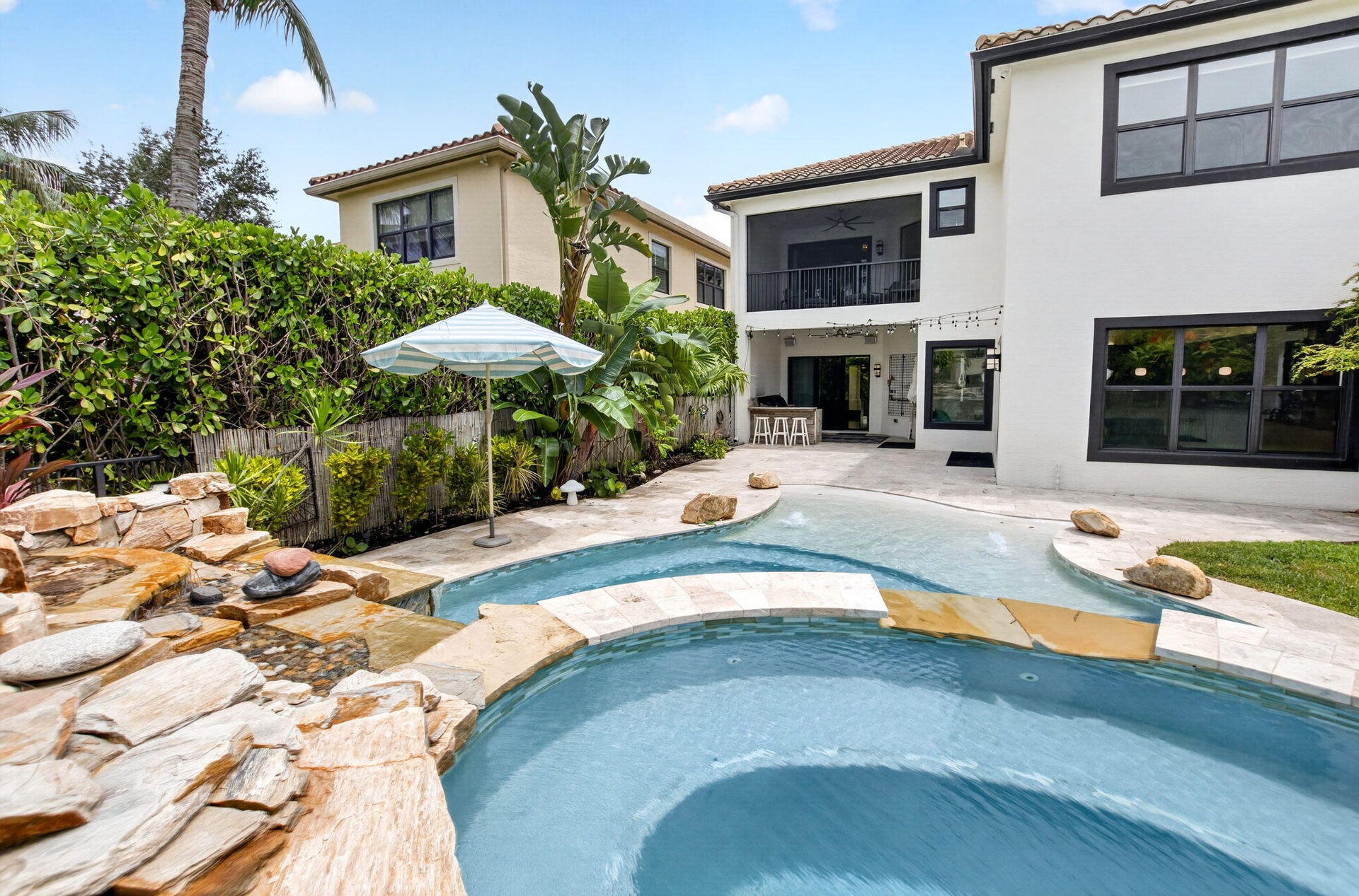 Backyard oasis featuring a custom rock waterfall, integrated pool and spa, and a spacious paver patio