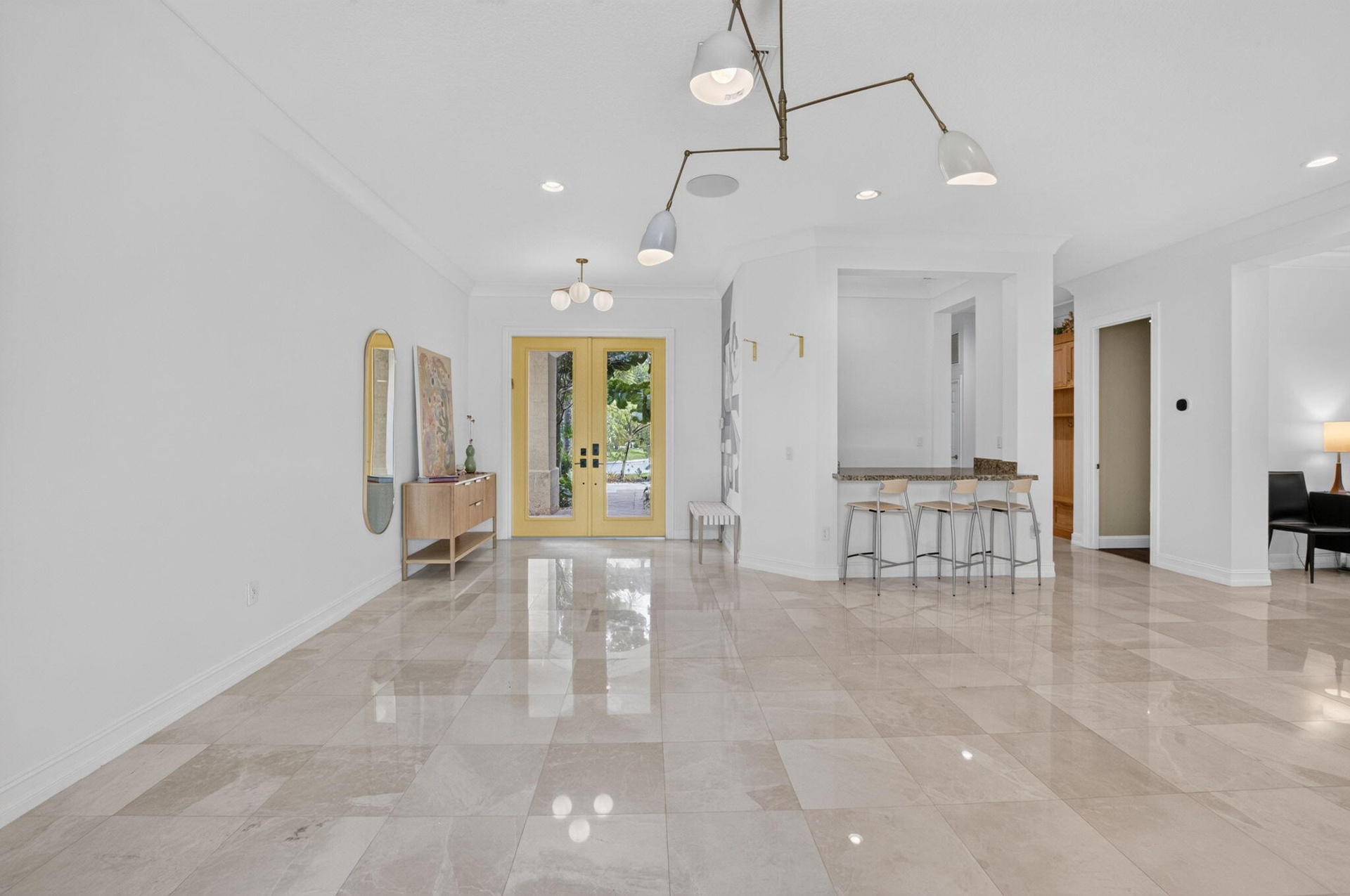 Spacious entry foyer featuring large format tile flooring, a built-in wet bar with seating, recessed lighting, and a contemporary ceiling light fixtur