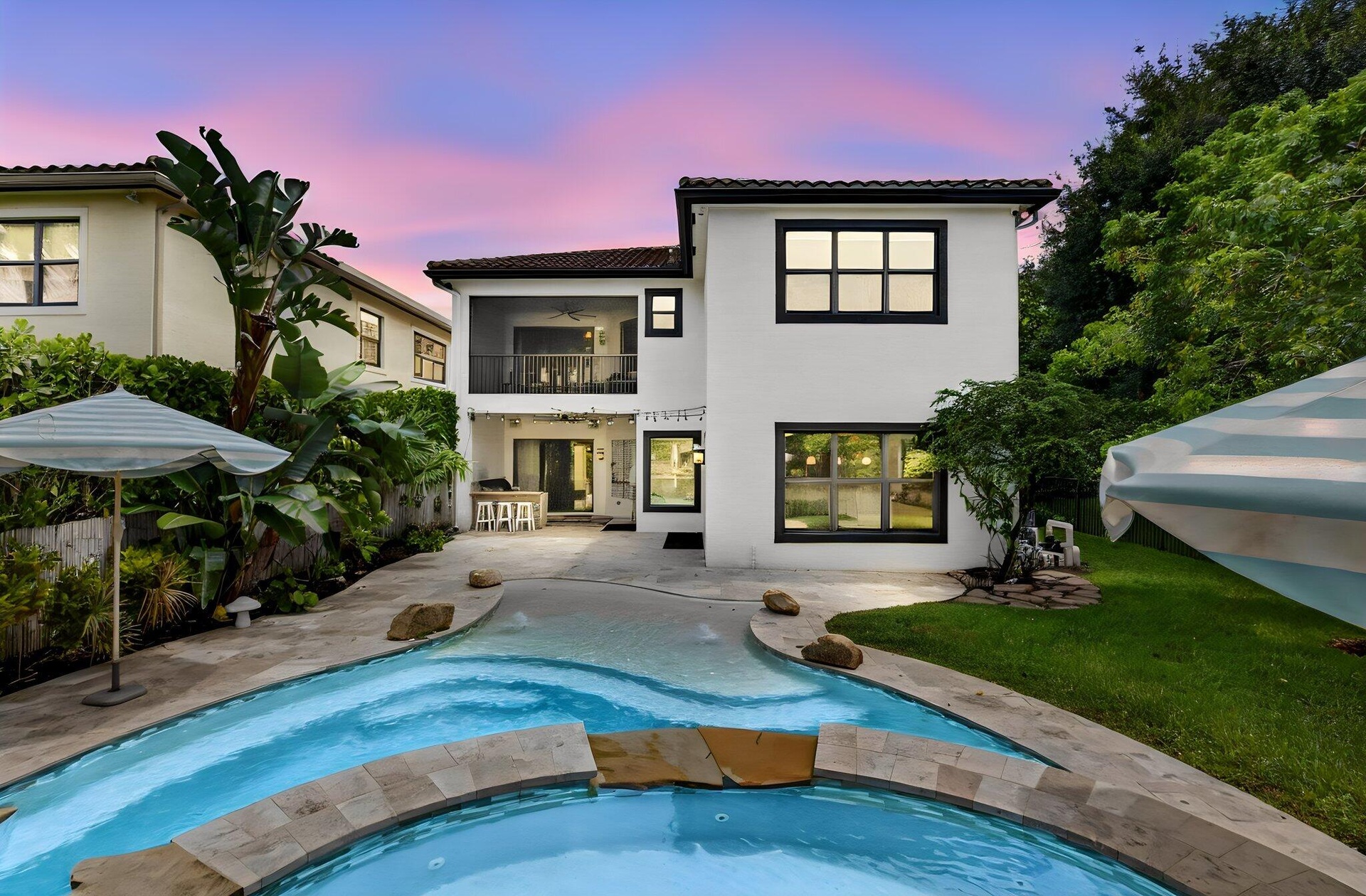 Backyard oasis featuring a freeform swimming pool, expansive paved patio, and a built-in outdoor kitchen