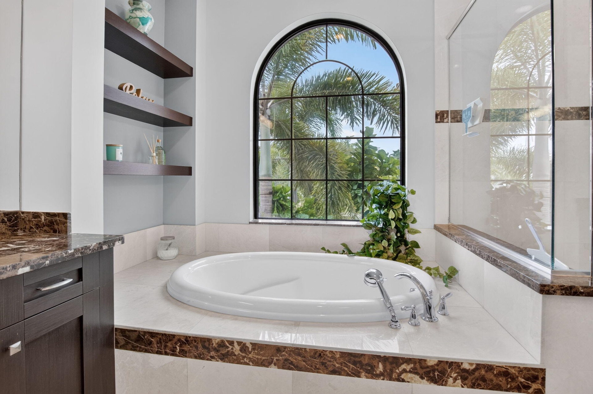 Soaking tub with chrome fixtures, set against an arched window with grid panes
