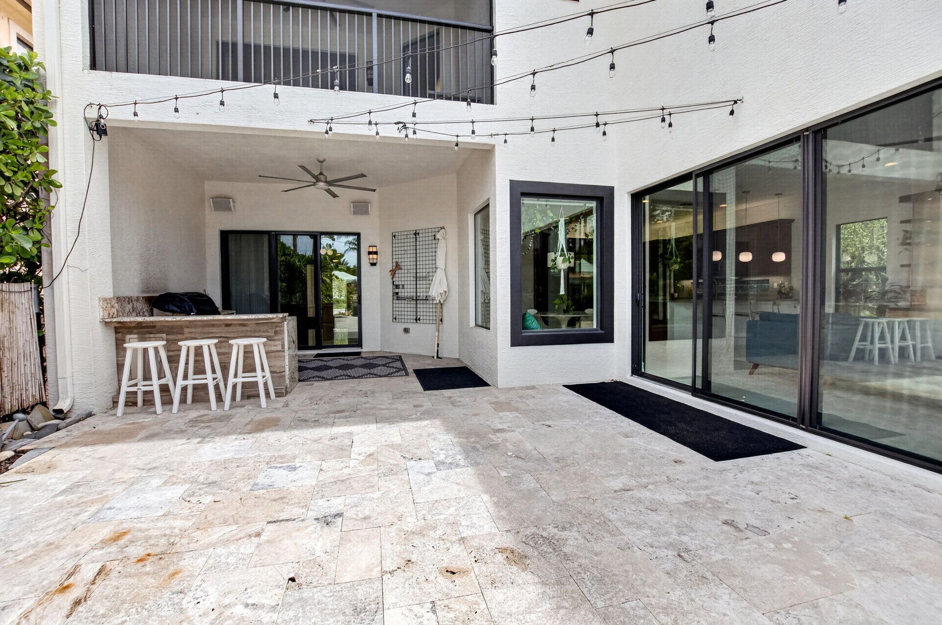 Spacious outdoor patio featuring natural stone flooring, an integrated outdoor bar with a stone countertop, a ceiling fan, and large sliding glass doo