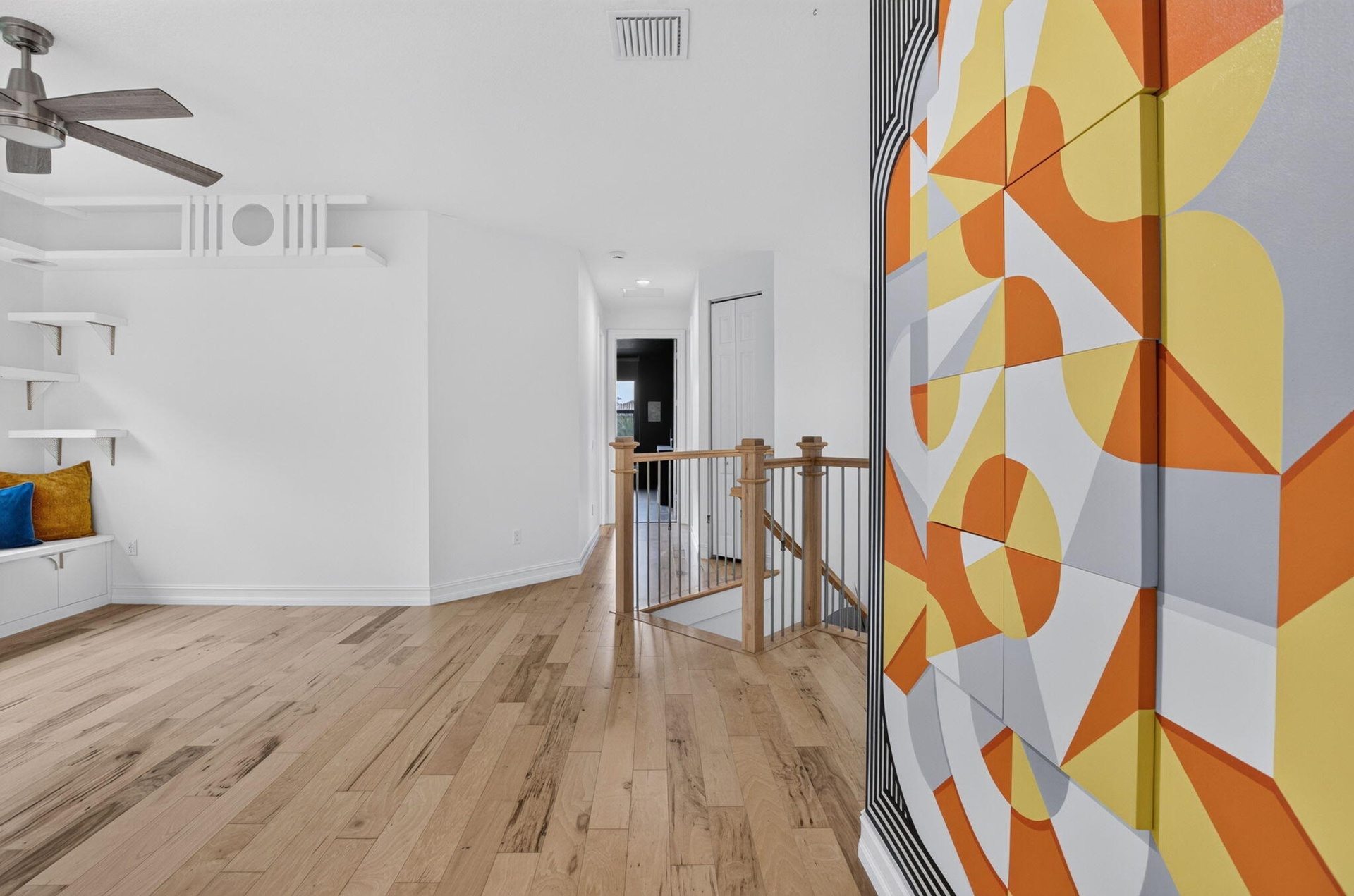 Open interior featuring wood-finish flooring, a built-in window bench, white floating shelves, and a ceiling fan