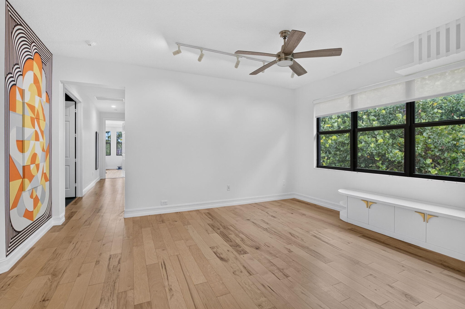 Spacious room featuring wood-finish flooring, white walls, and a large window with black framing