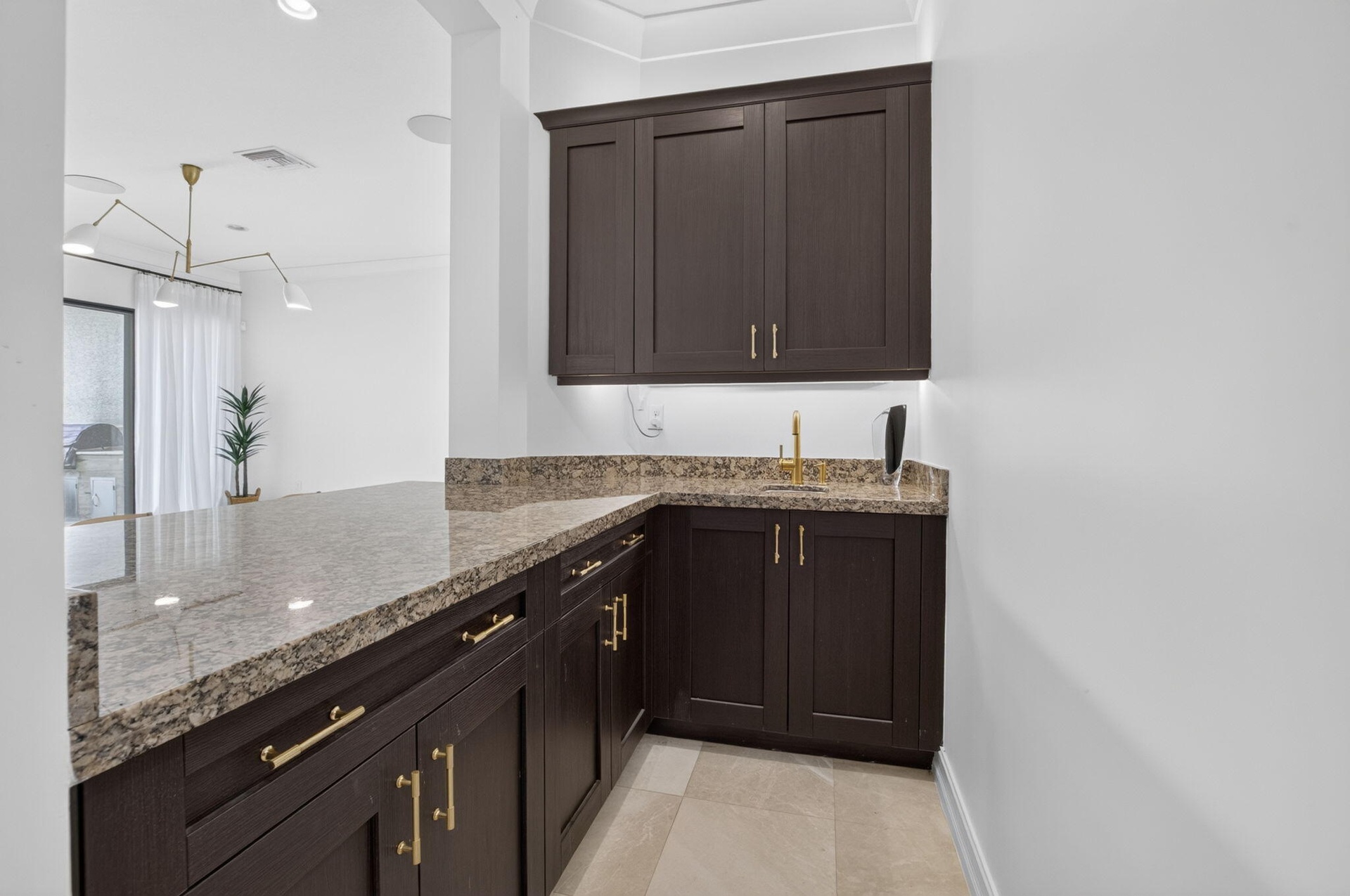 Custom built-in cabinetry with gold-tone hardware, a light-toned patterned countertop, and an undermount sink with a gold-tone faucet
