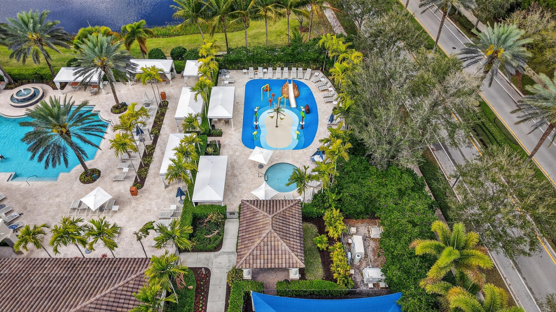 Resort-style pool area featuring a large swimming pool, separate splash pad, spa, and ample lounge seating with cabanas