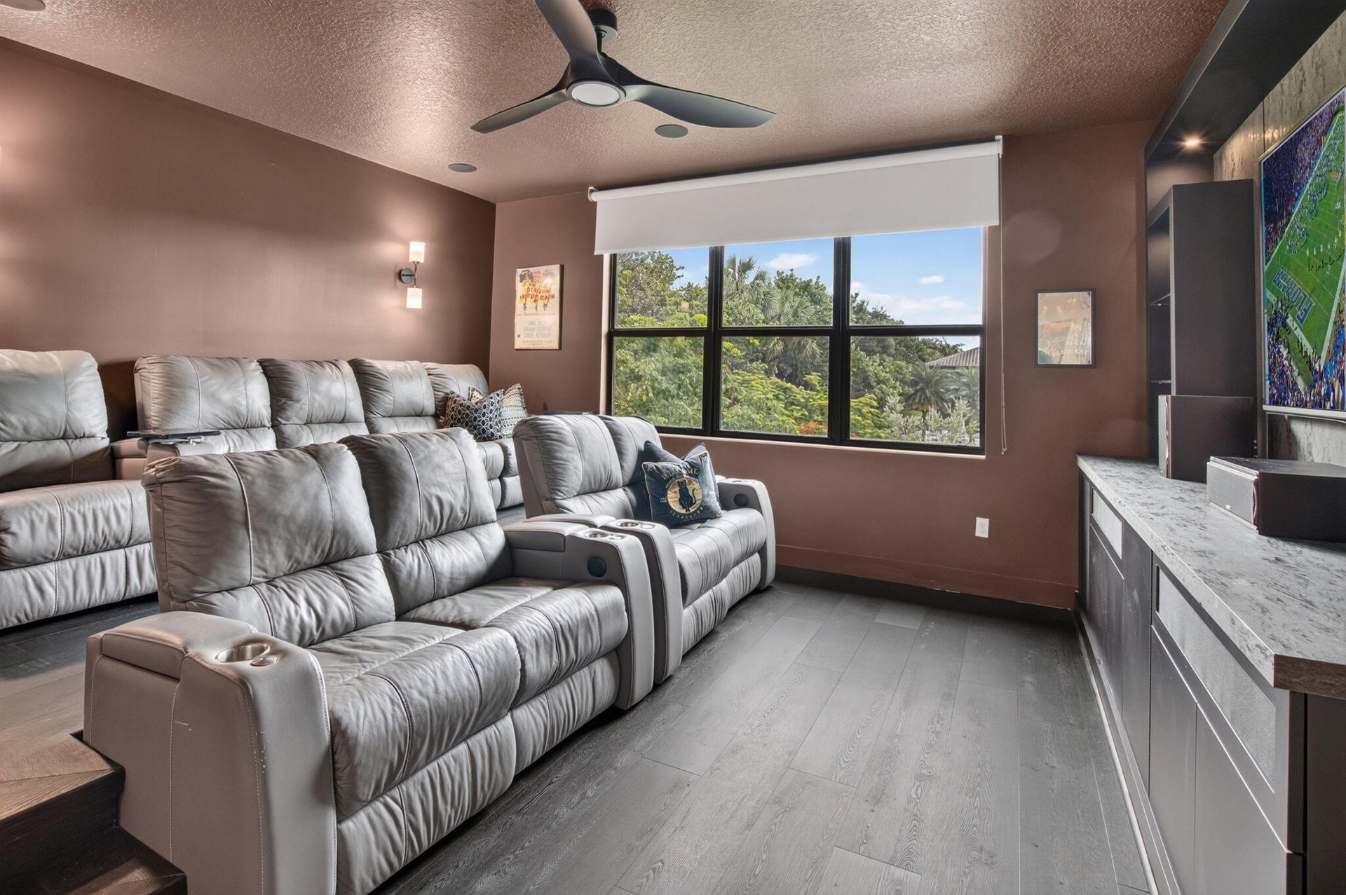 Dedicated media room featuring wood-finish flooring, a contemporary ceiling fan, and a built-in media console with a light-toned countertop