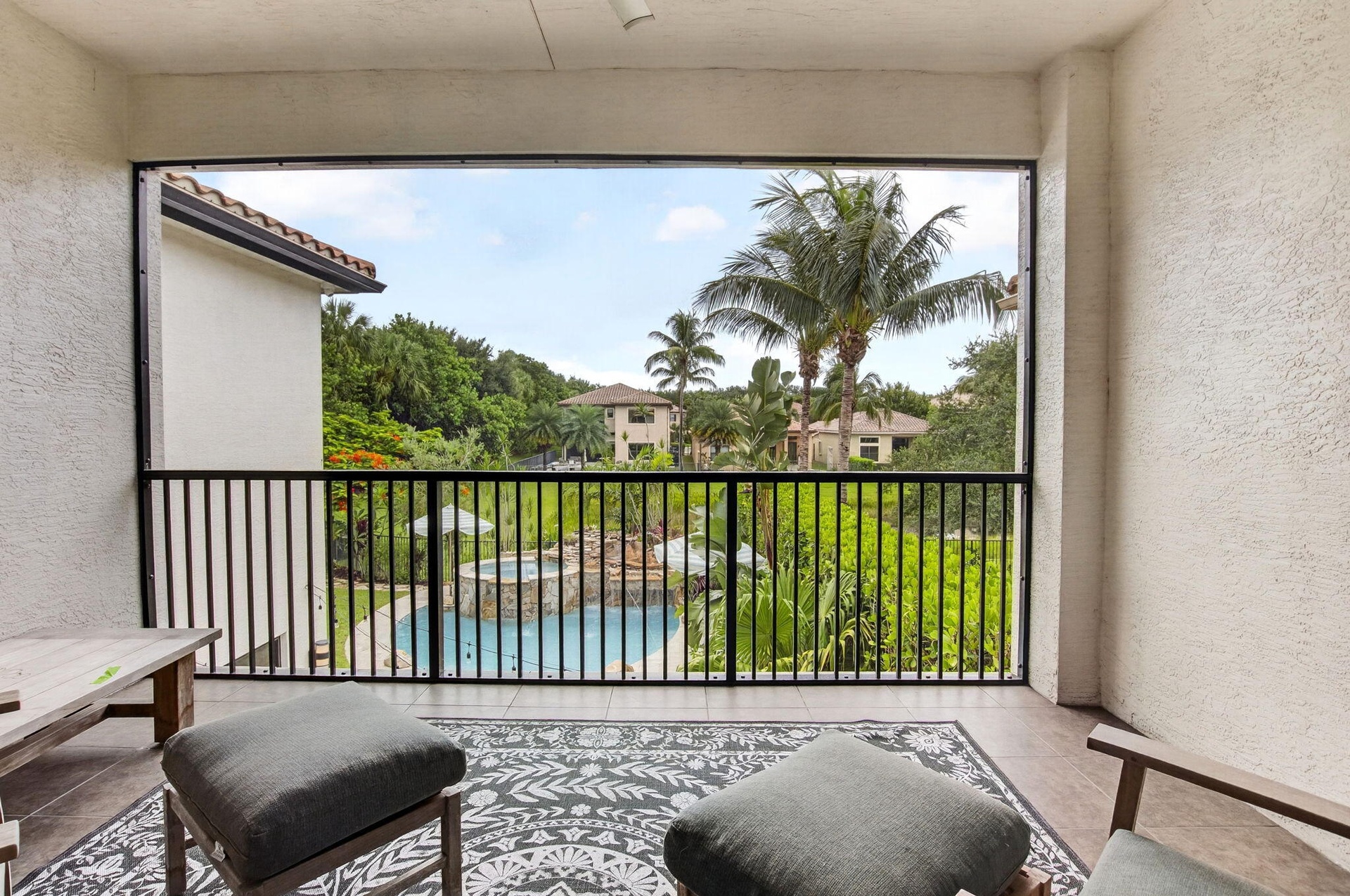Expansive balcony featuring a black metal railing, textured exterior walls, and tiled flooring