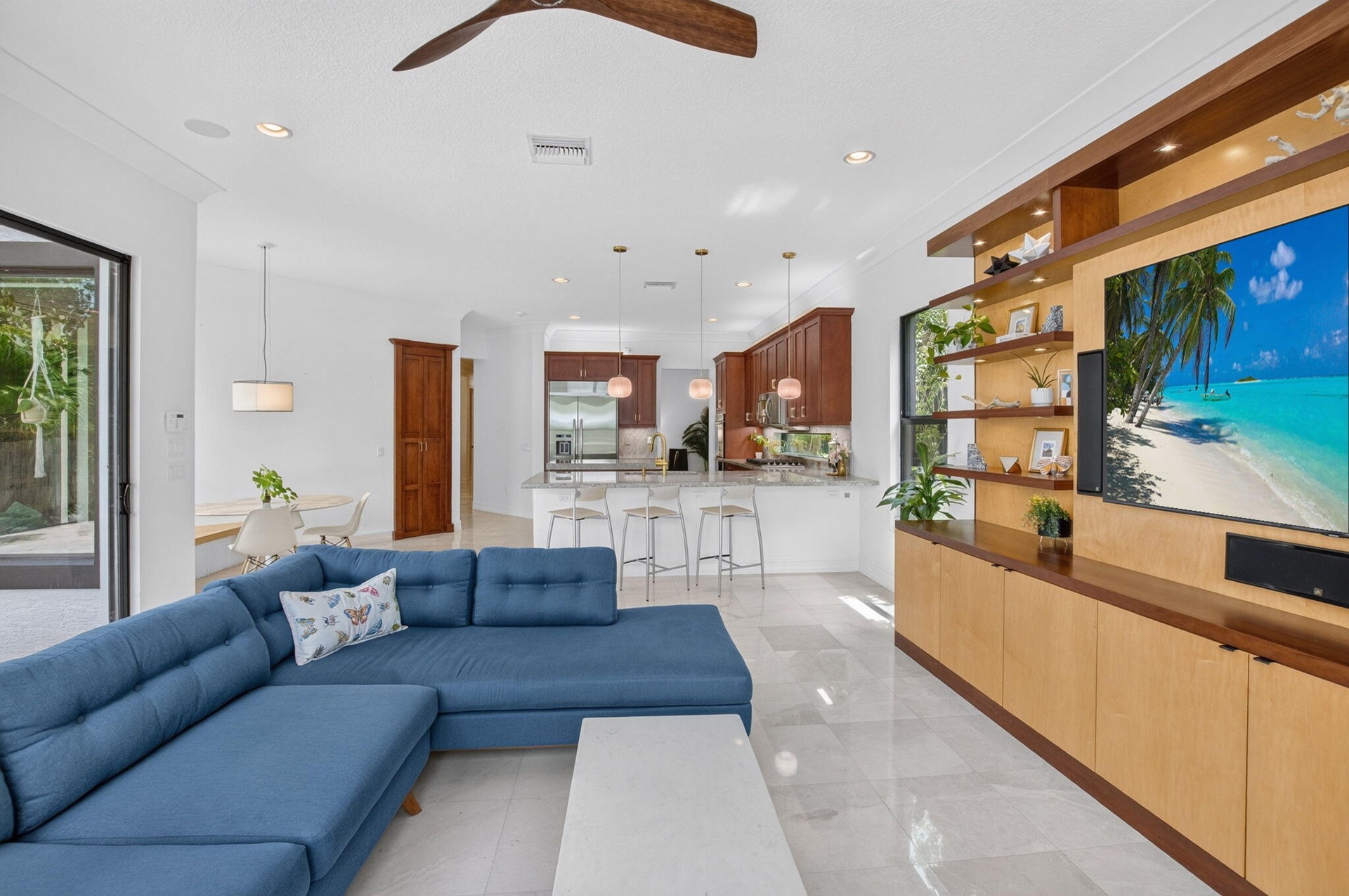 Open-concept living space with light-toned tile flooring, recessed lighting, a ceiling fan, and a built-in media center with shelving and lower cabine