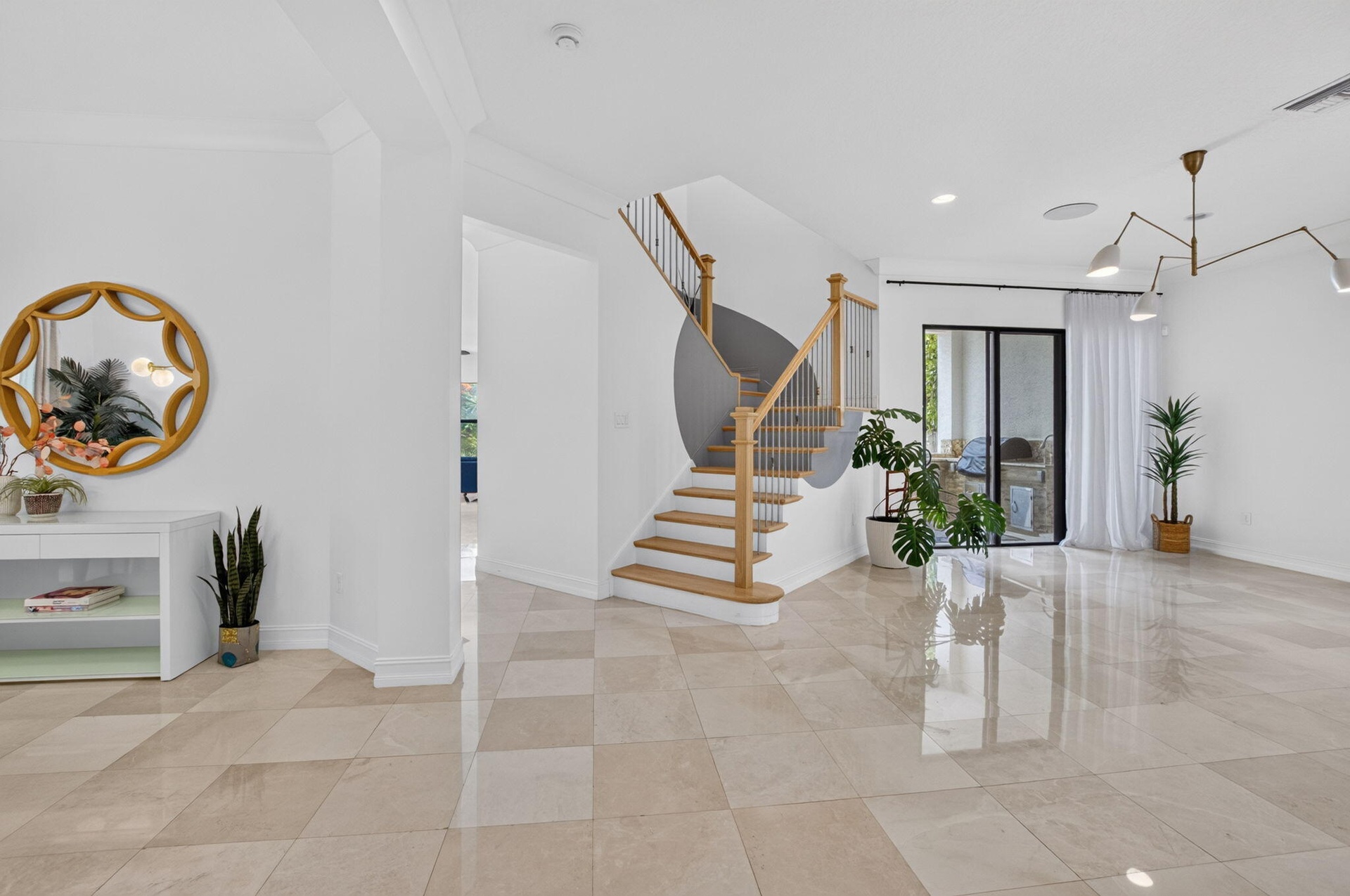 Bright entry foyer featuring diamond-patterned tile flooring and a central wooden staircase with black metal balusters
