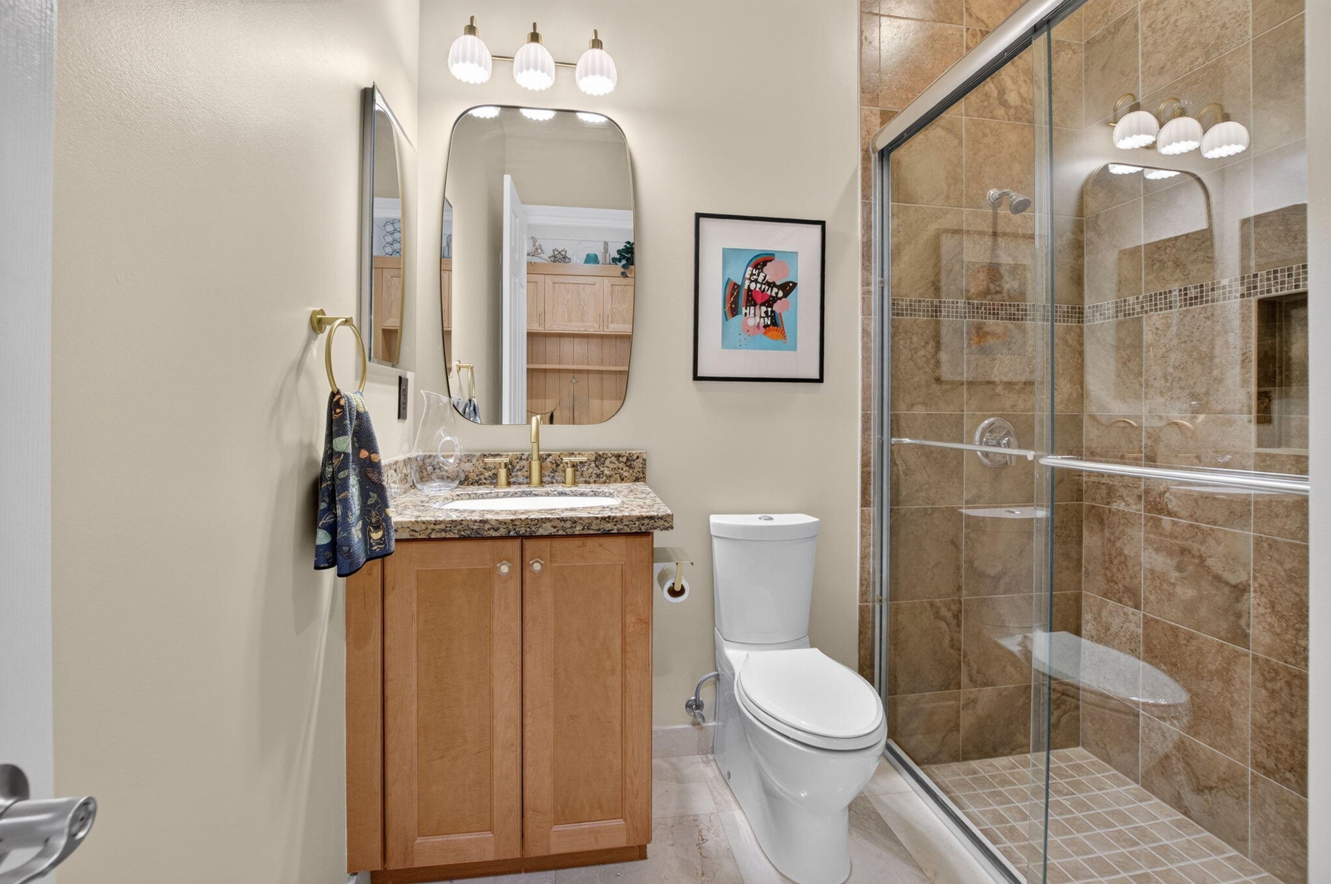 Bathroom featuring a single vanity with a granite-style countertop, wood-finish cabinetry, and a walk-in shower with tiled walls and a glass enclosure
