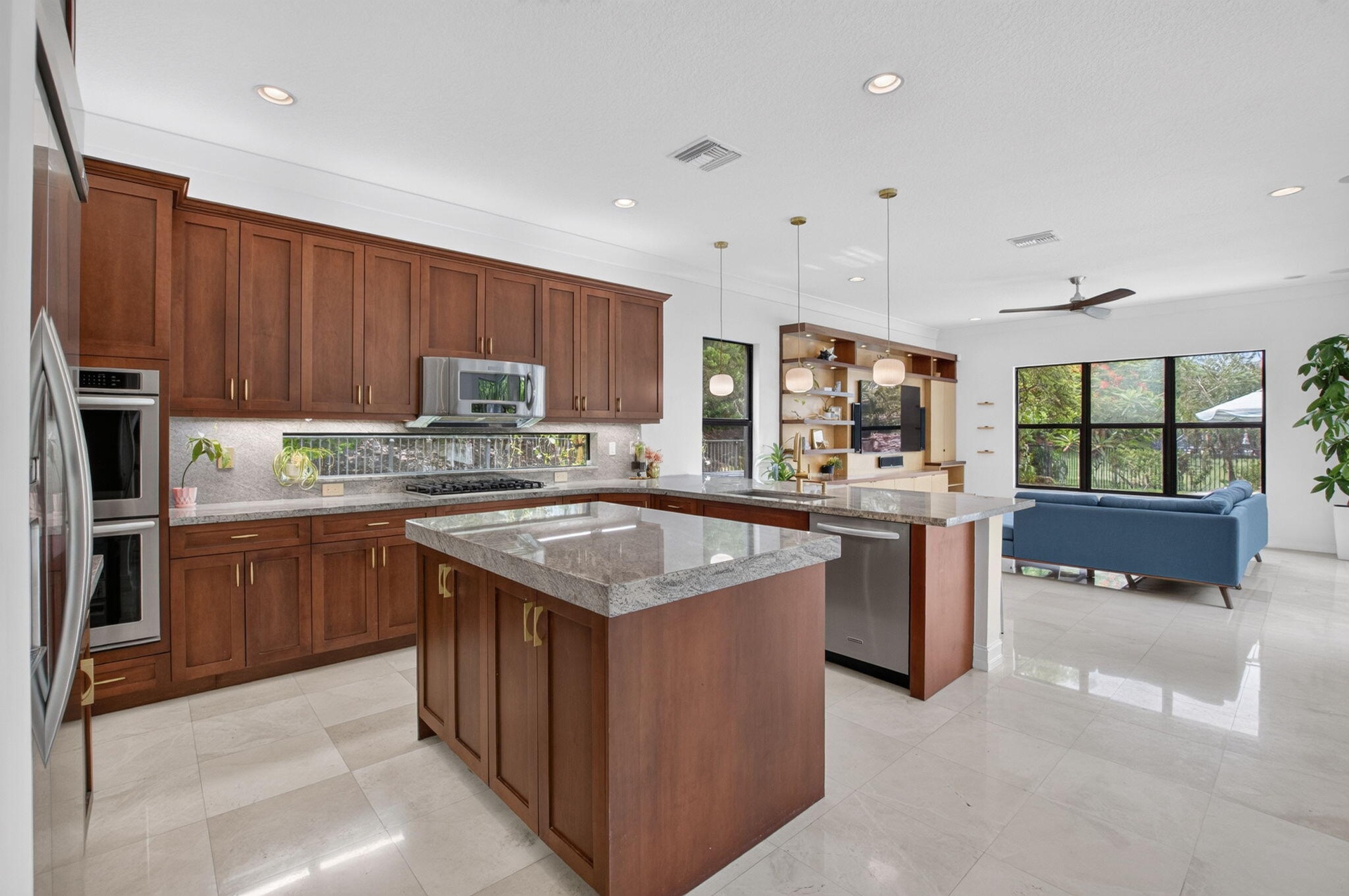 Gourmet kitchen featuring wood cabinetry, light-toned countertops, and stainless steel appliances, including double wall ovens