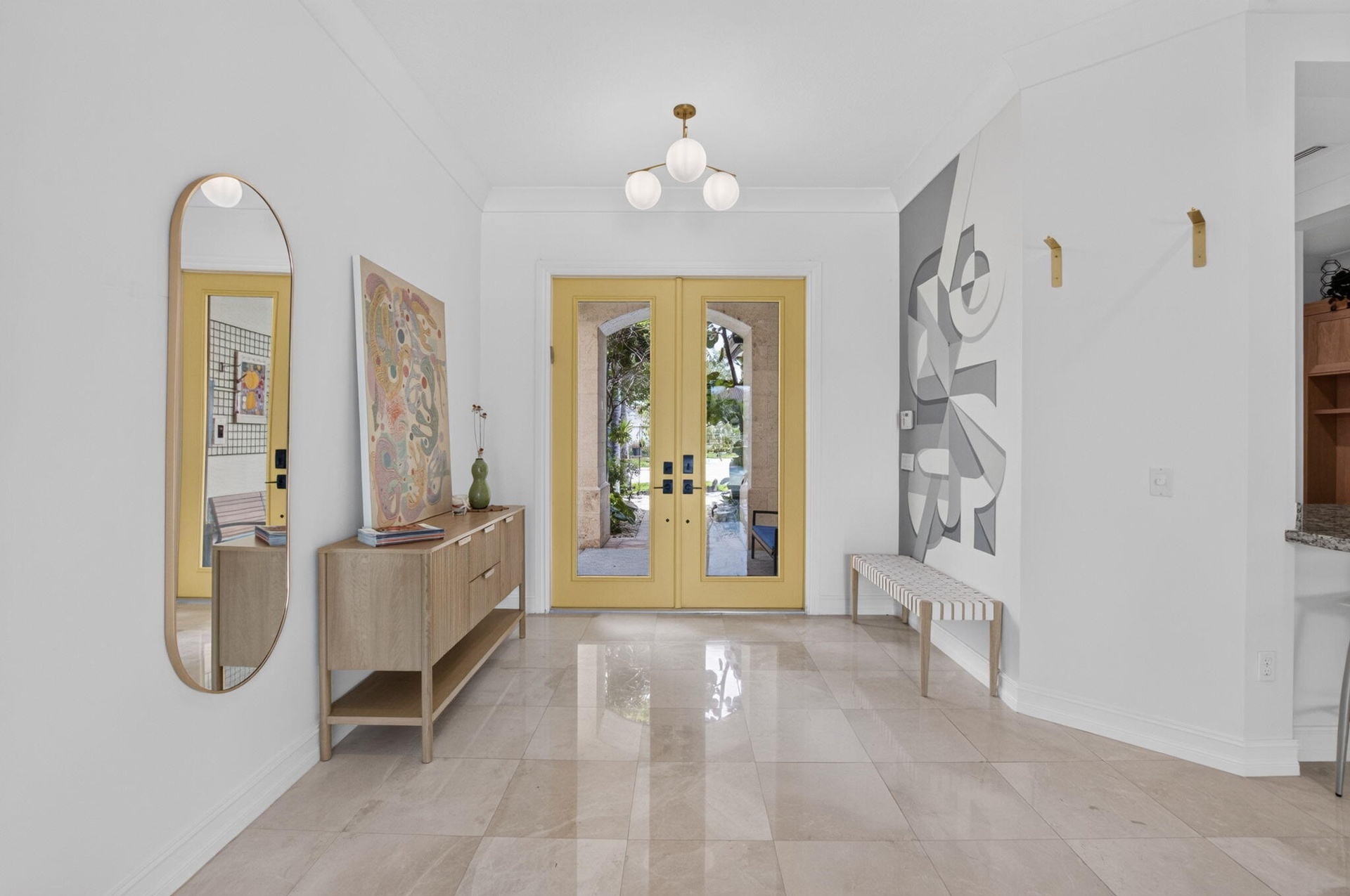 Spacious entryway featuring light-toned large format tile flooring, crown molding, and a contemporary spherical chandelier