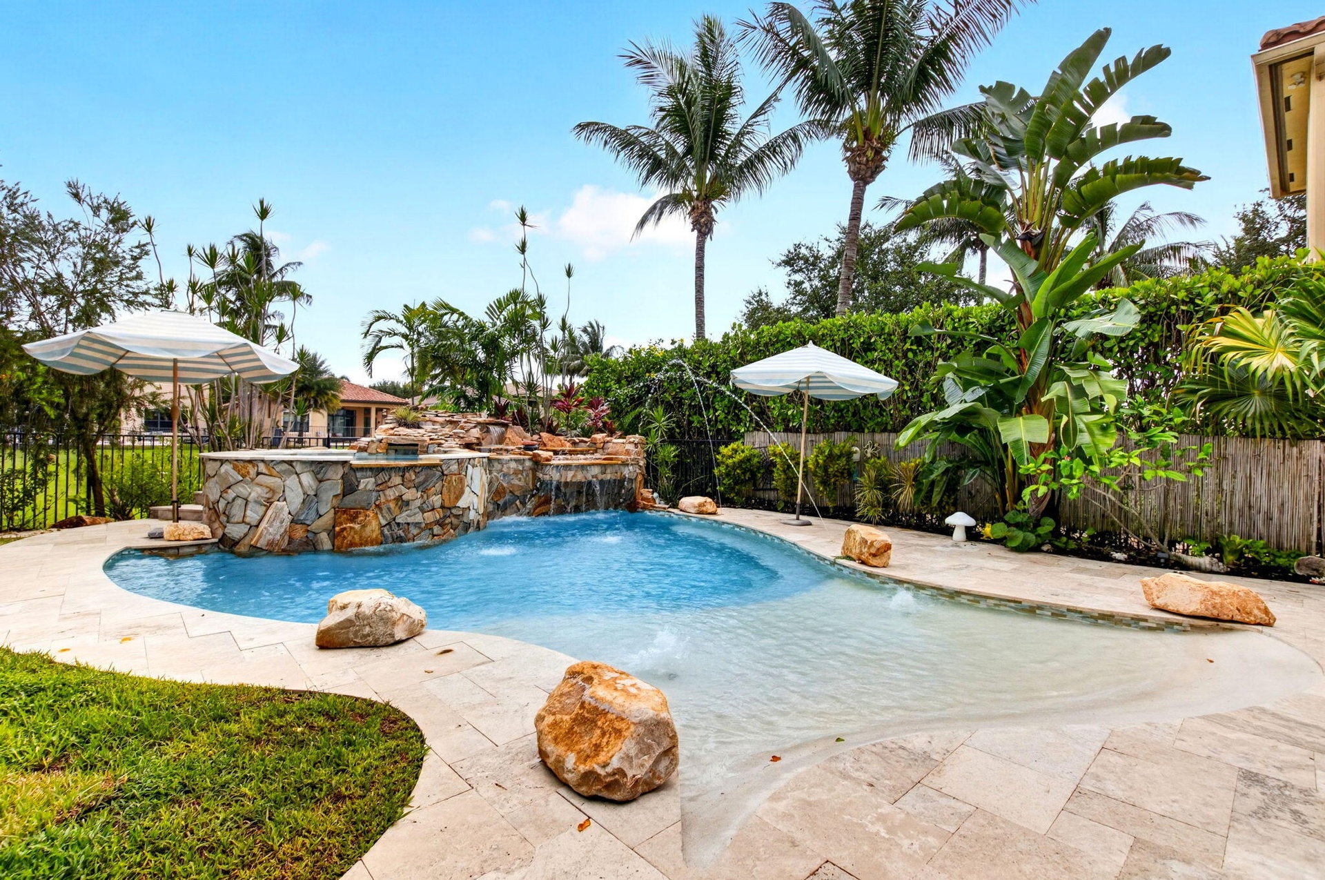 Freeform swimming pool featuring a rock waterfall, integrated spa, and an expansive sun shelf