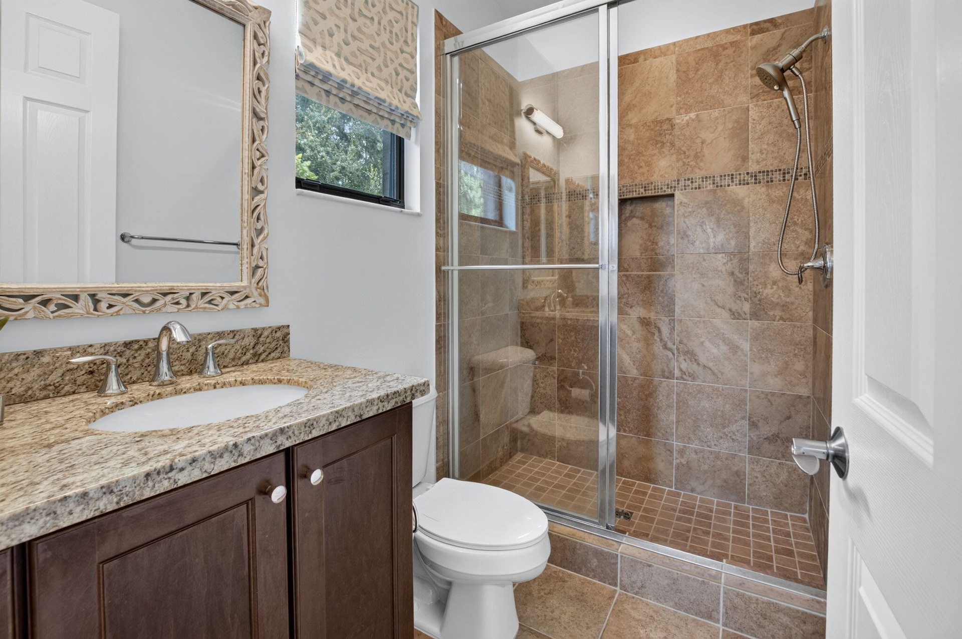 Bathroom featuring a walk-in shower with full-height tile surround and glass enclosure, a built-in shower niche, and a dual-function shower head