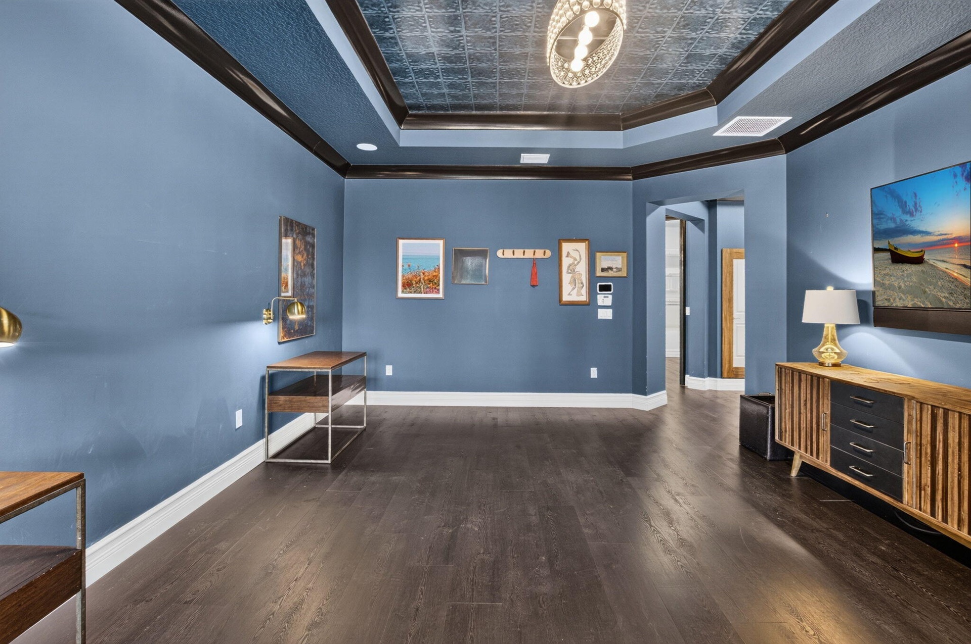Spacious room featuring dark wood-finish flooring, blue walls, and a multi-tiered ceiling with a decorative patterned inlay
